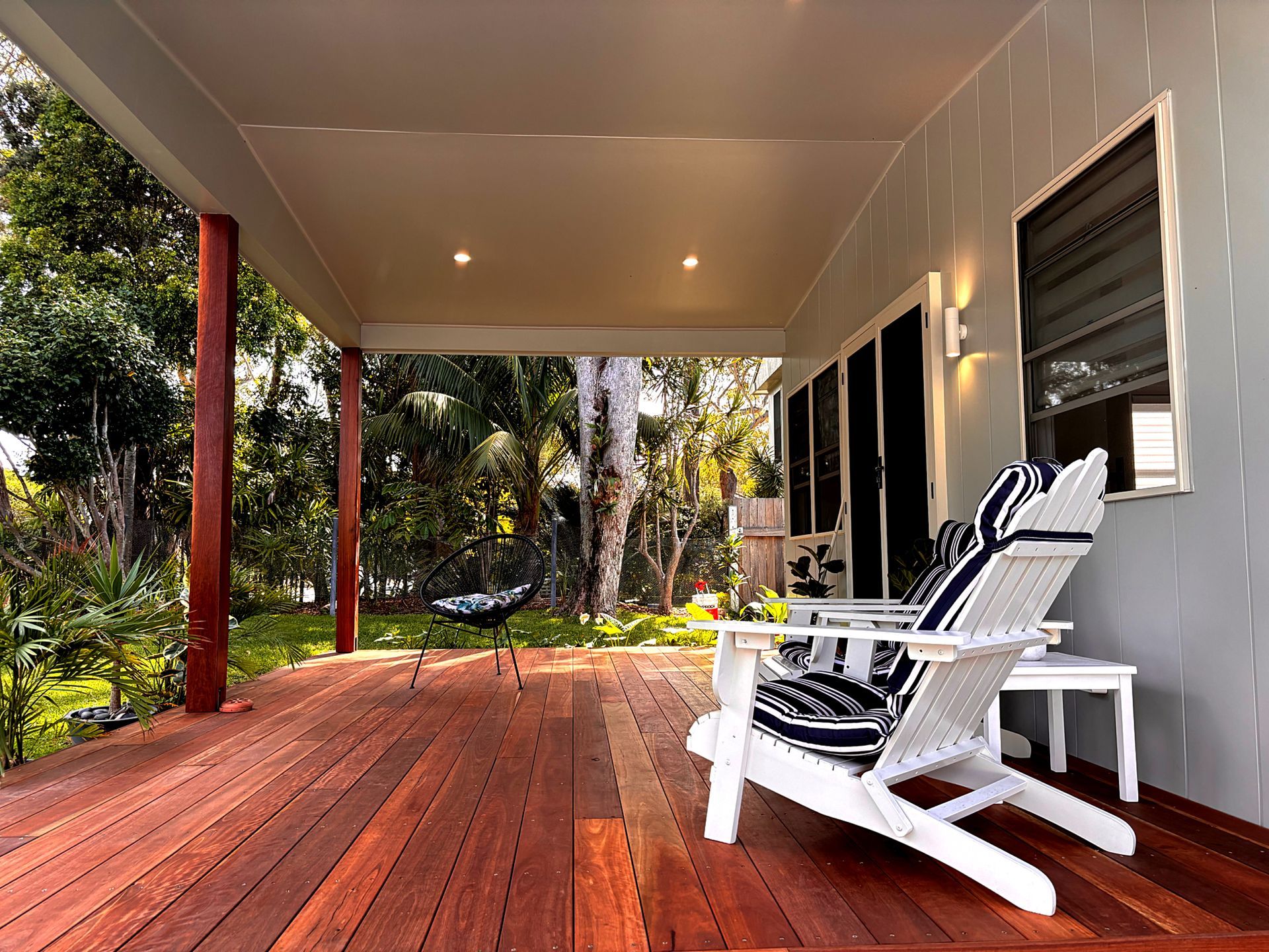 Two white chairs are sitting on a wooden deck with downlights and wall pendants. Home Electrical