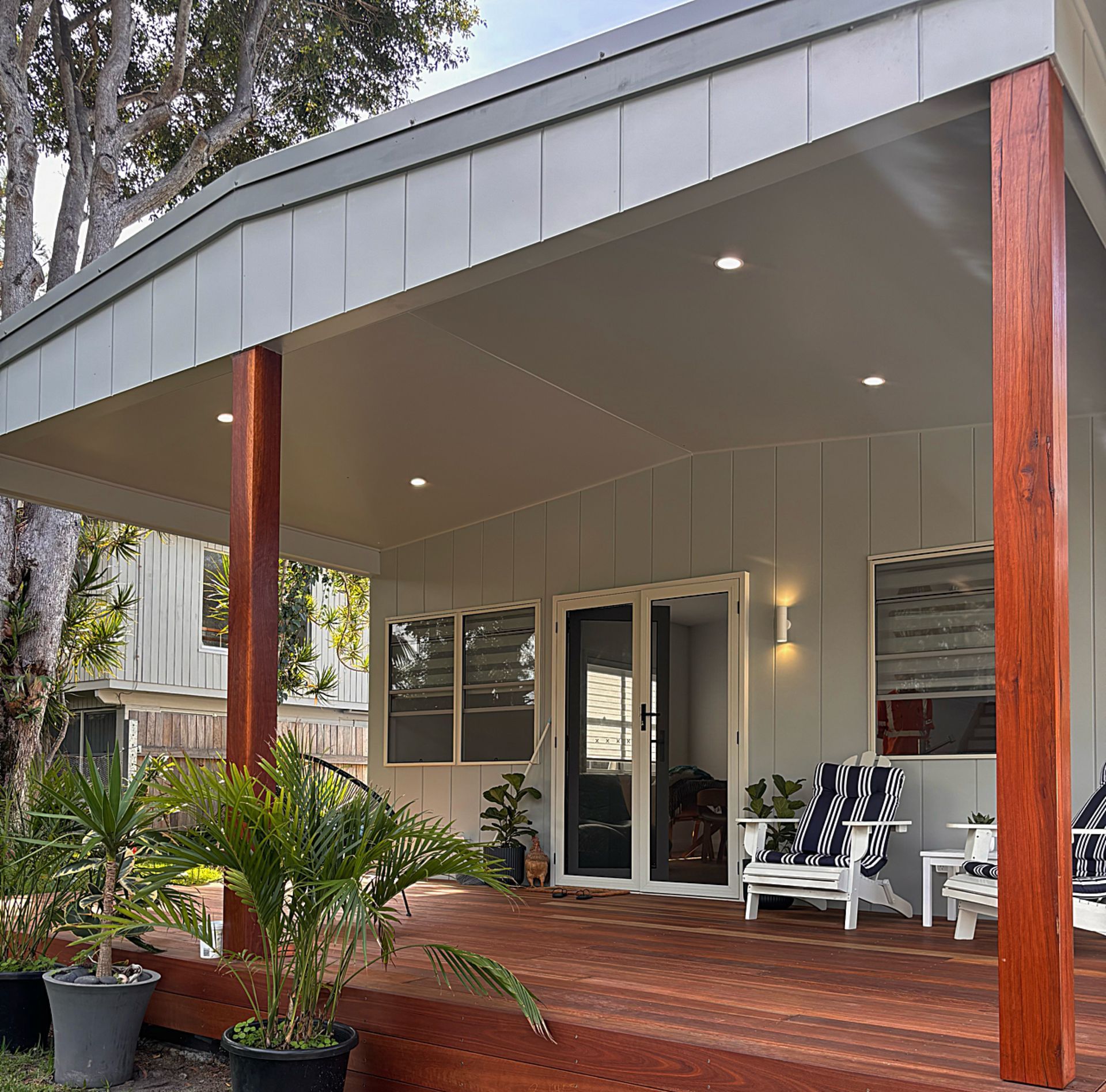  Home Electrical - A house with a covered porch with chairs and potted plants with exterior down lights and wall pendants. 