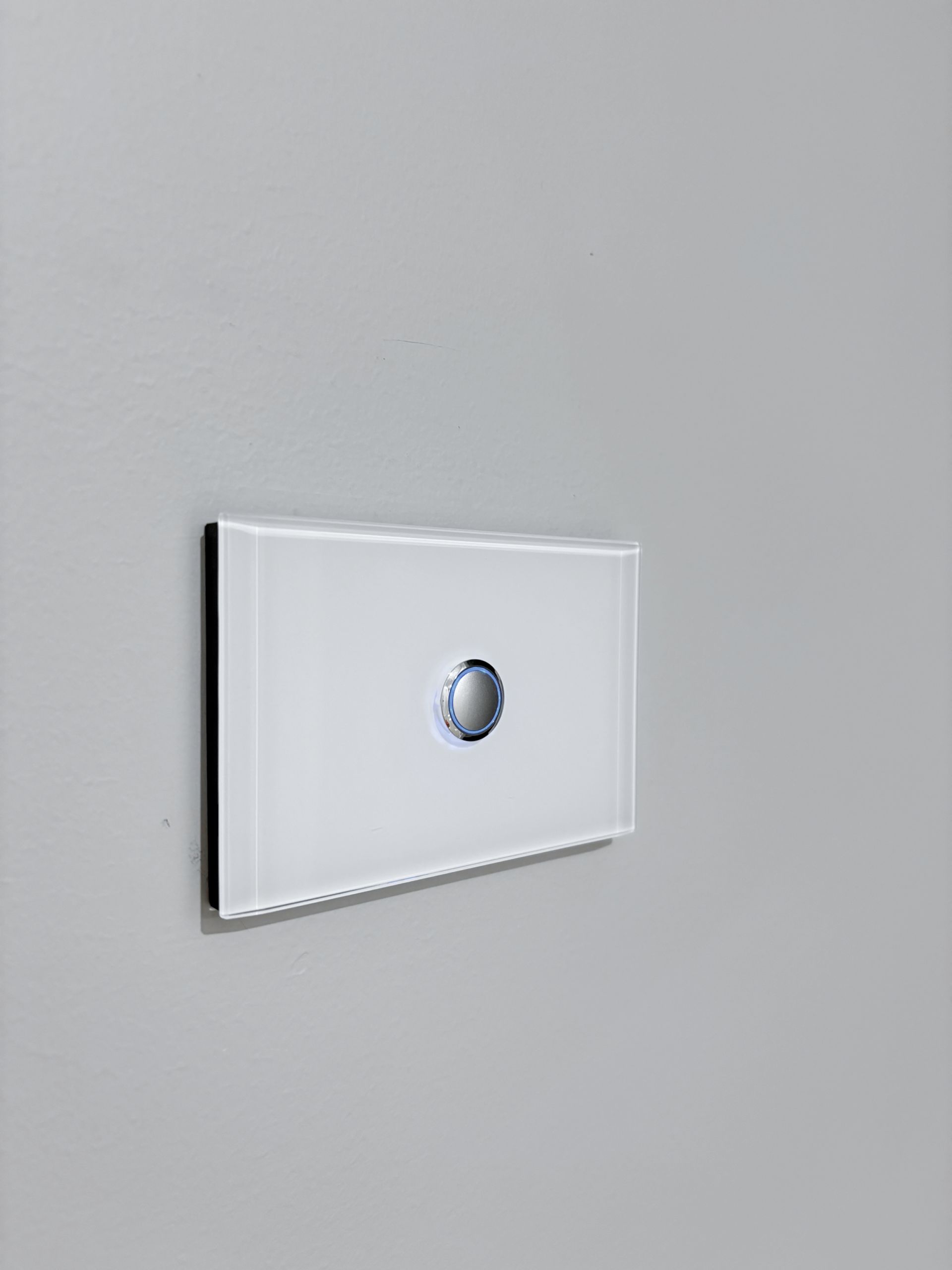 A white light switch is mounted on a gray wall.