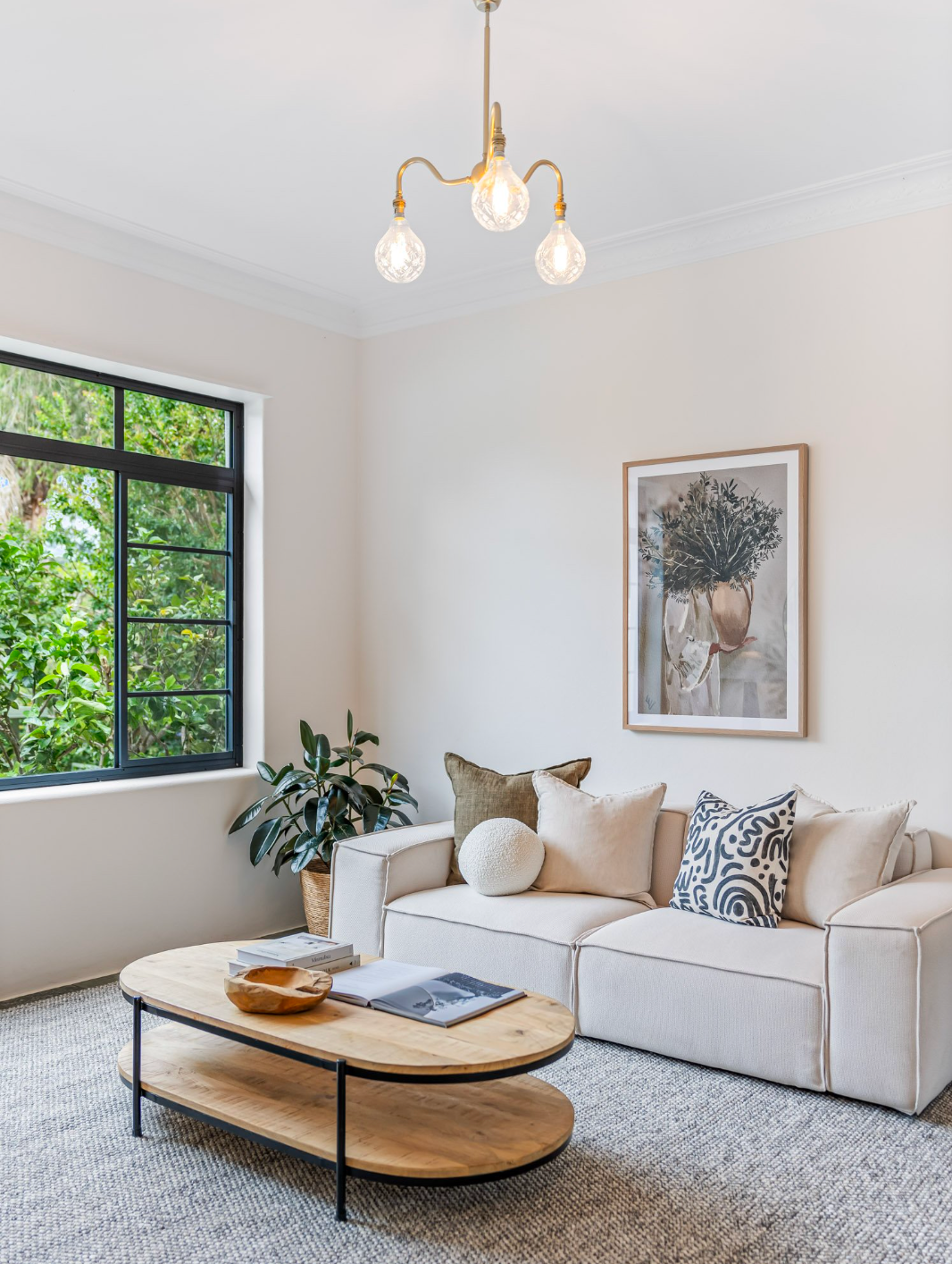 A living room with a couch , coffee table ,  ceiling lighting and window.