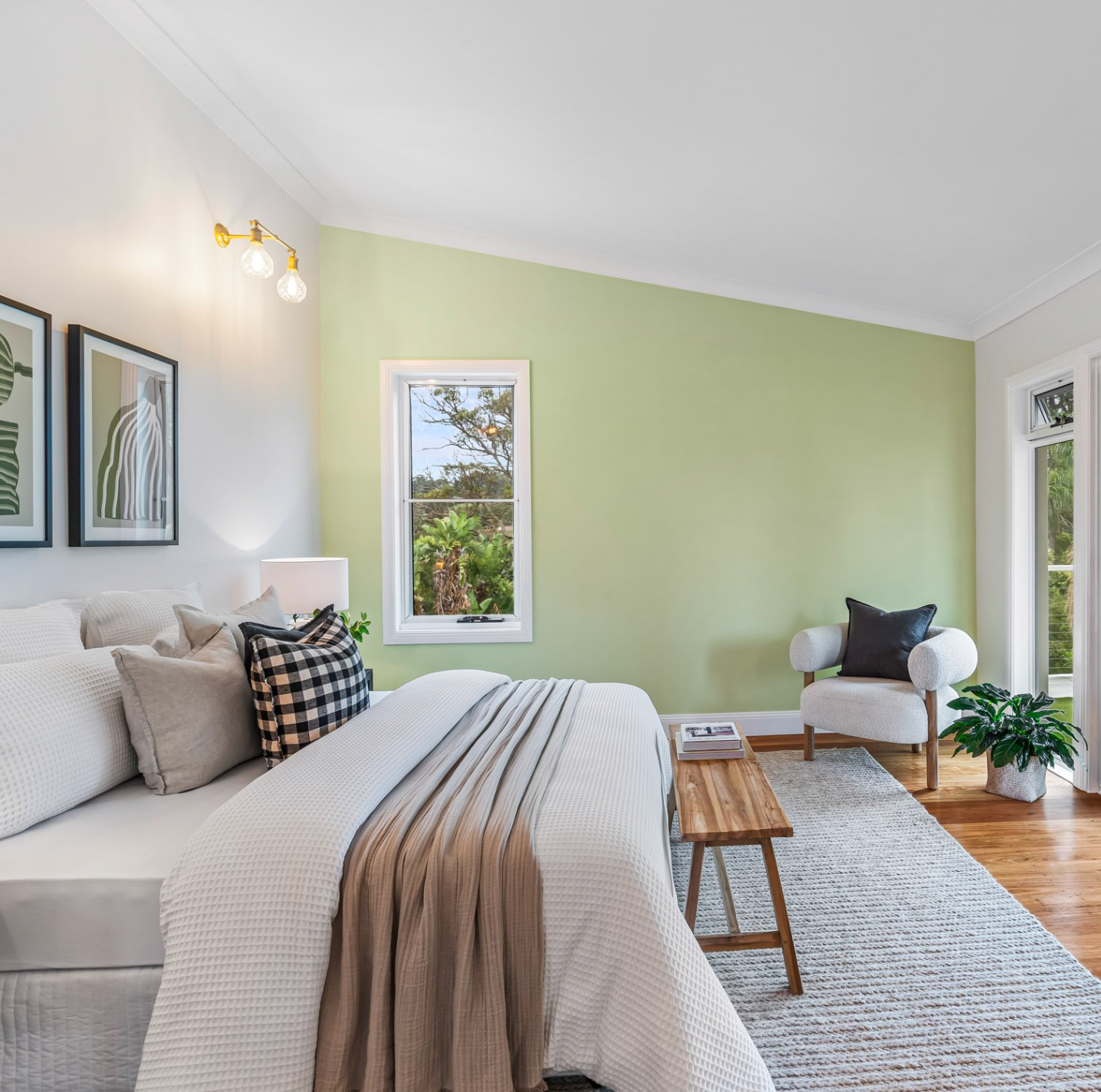 A bedroom with a bed , fat shack wall pendant light, chair , rug and green walls