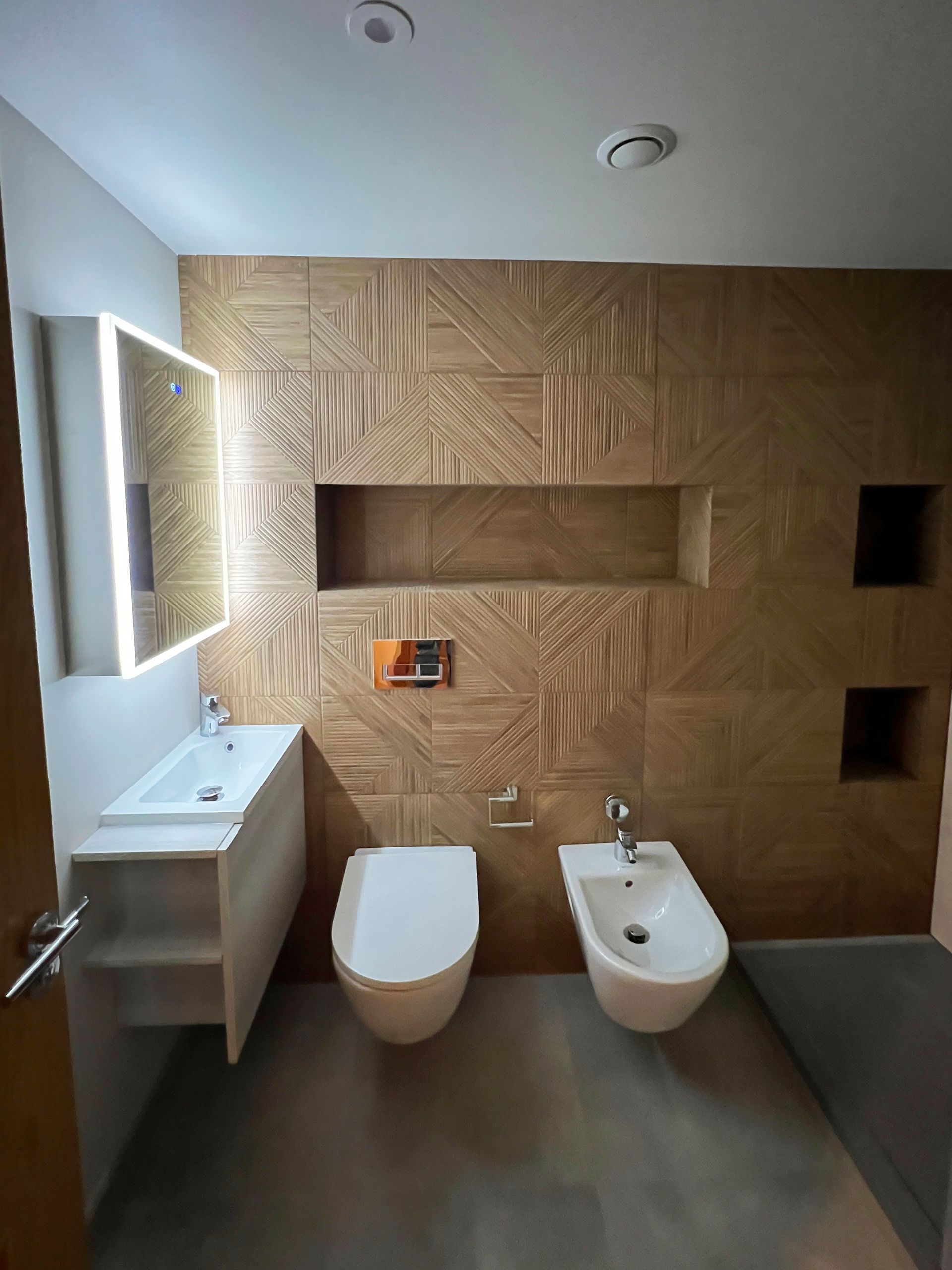 Wet room with sink, toilette, bidet and walk-in shower, with additional alcoves that are back-lit