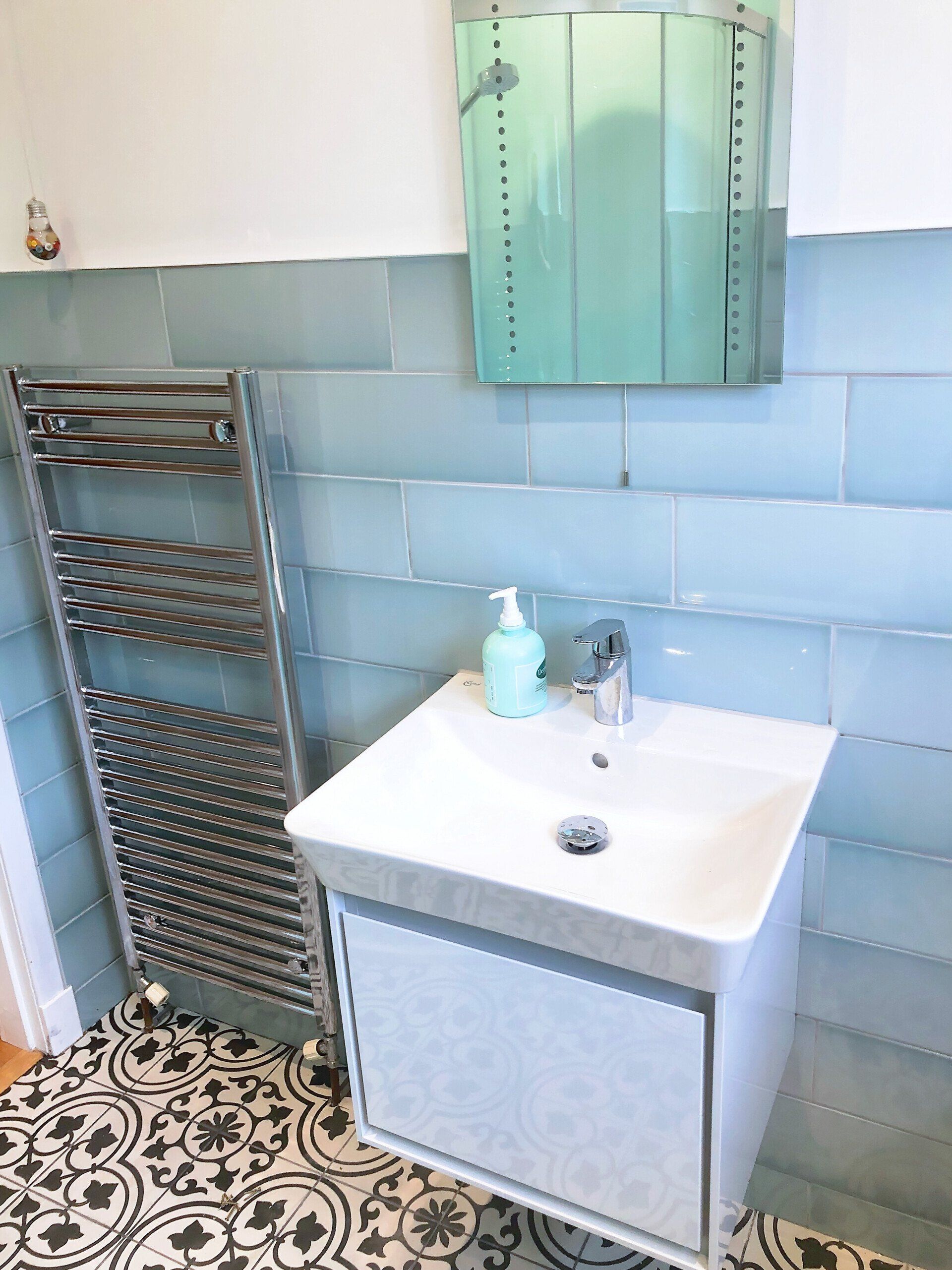 A bathroom with a sink , mirror and towel rack.