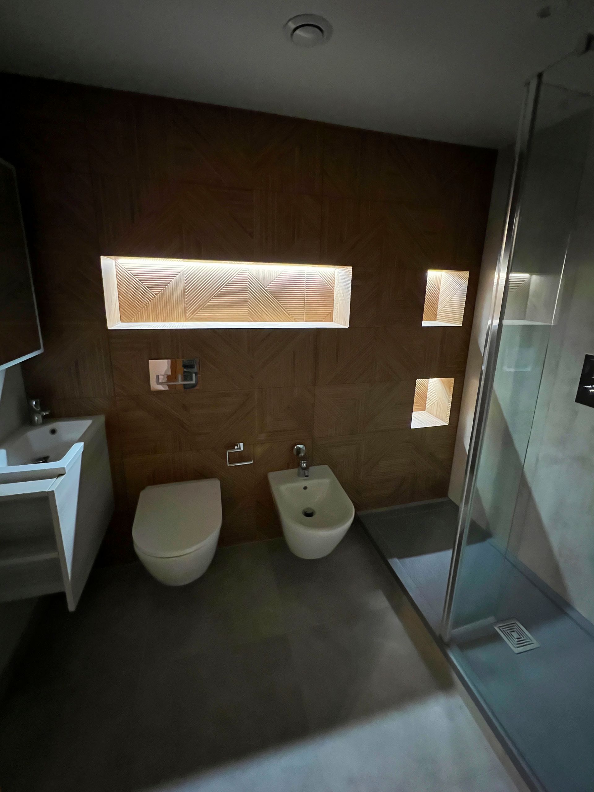 Wet room with sink, toilette, bidet and walk-in shower, with additional alcoves that are back-lit