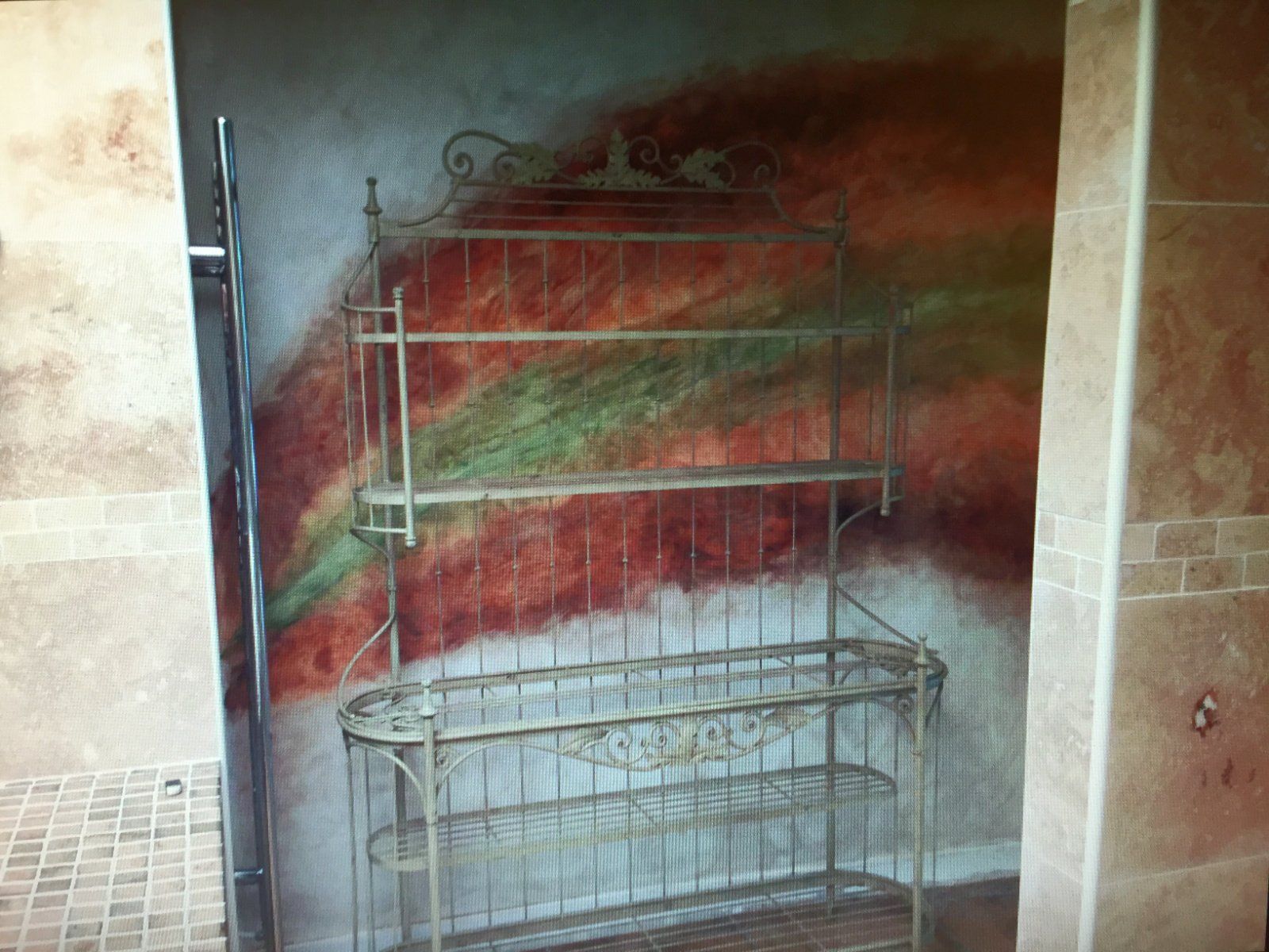 A metal shelf in a room with a painting on the wall behind it