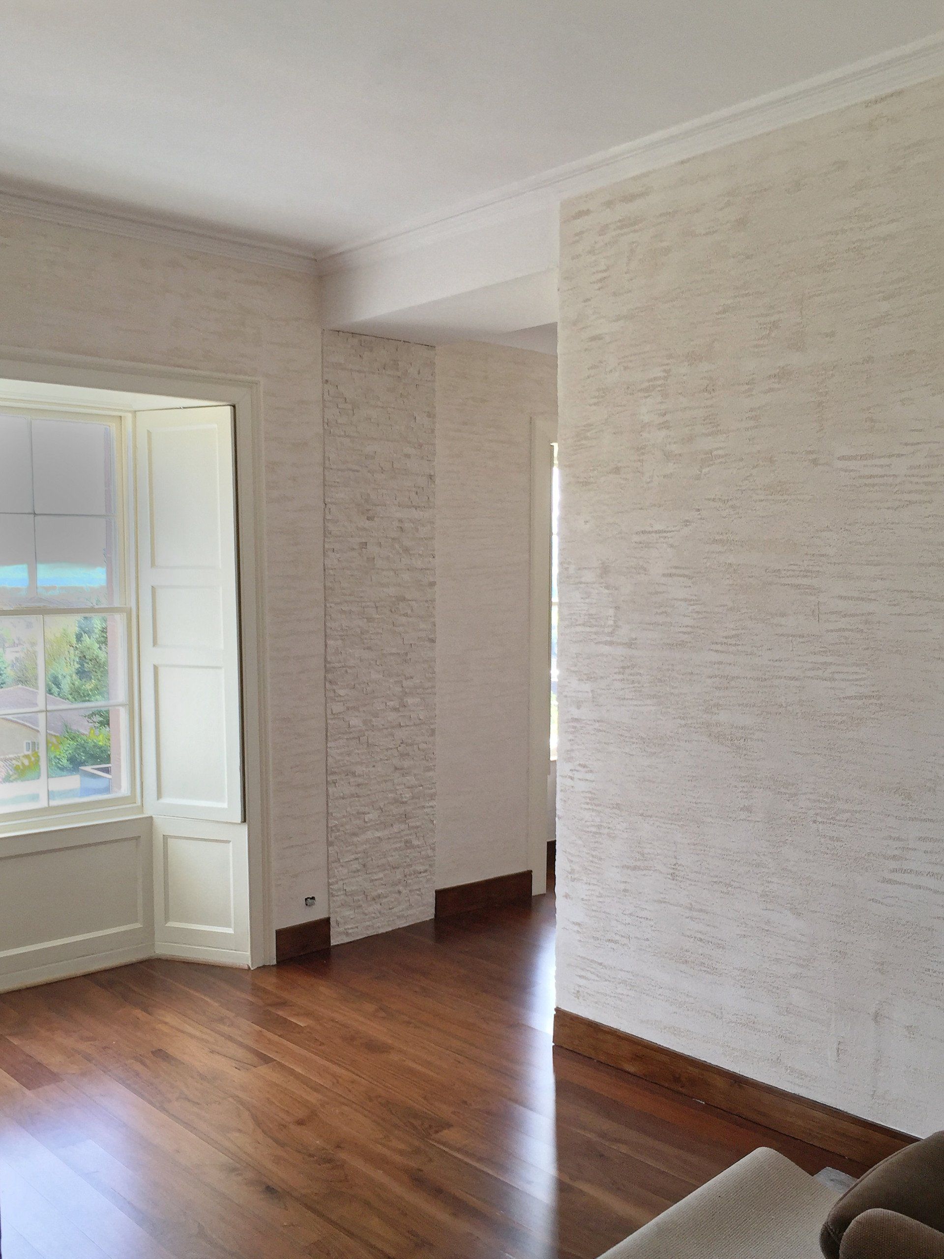 A living room with hardwood floors, white walls and a window.
