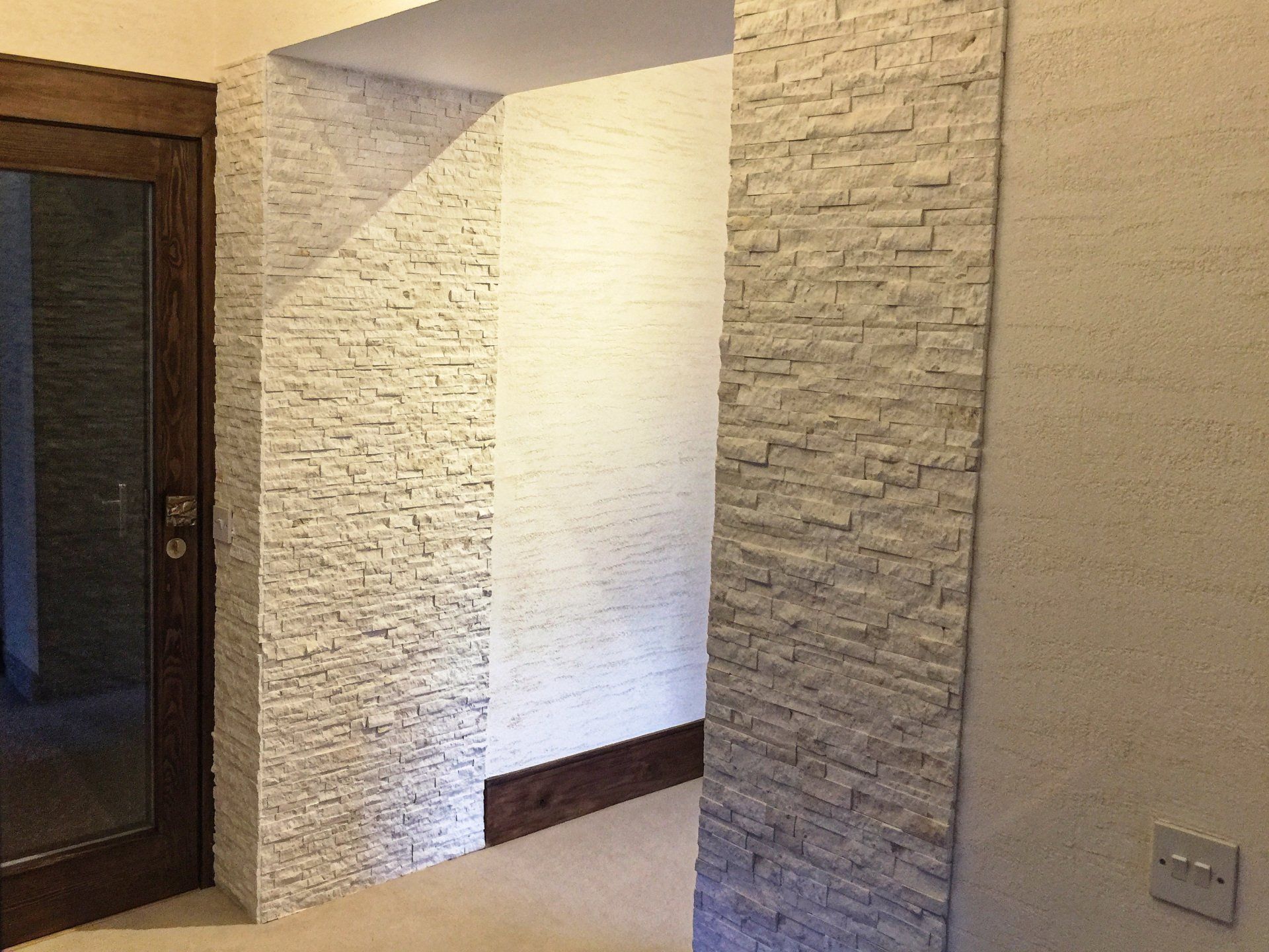 A hallway with brick walls and a glass door.