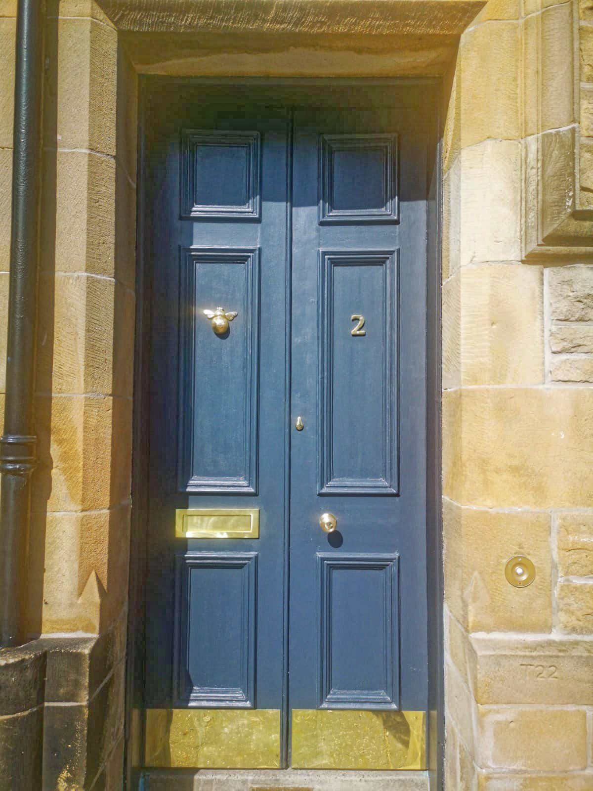 A blue door with the number 2 on it is on a stone building.
