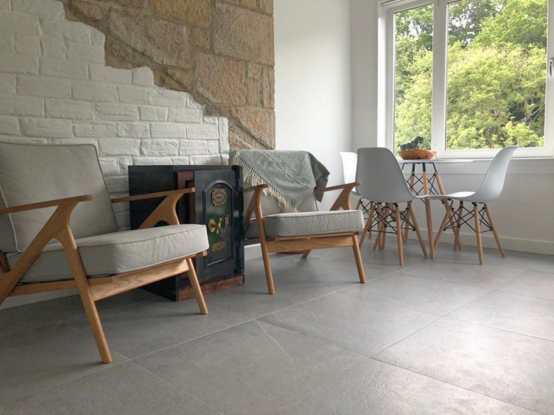 A living room with two chairs , a table and a window.
