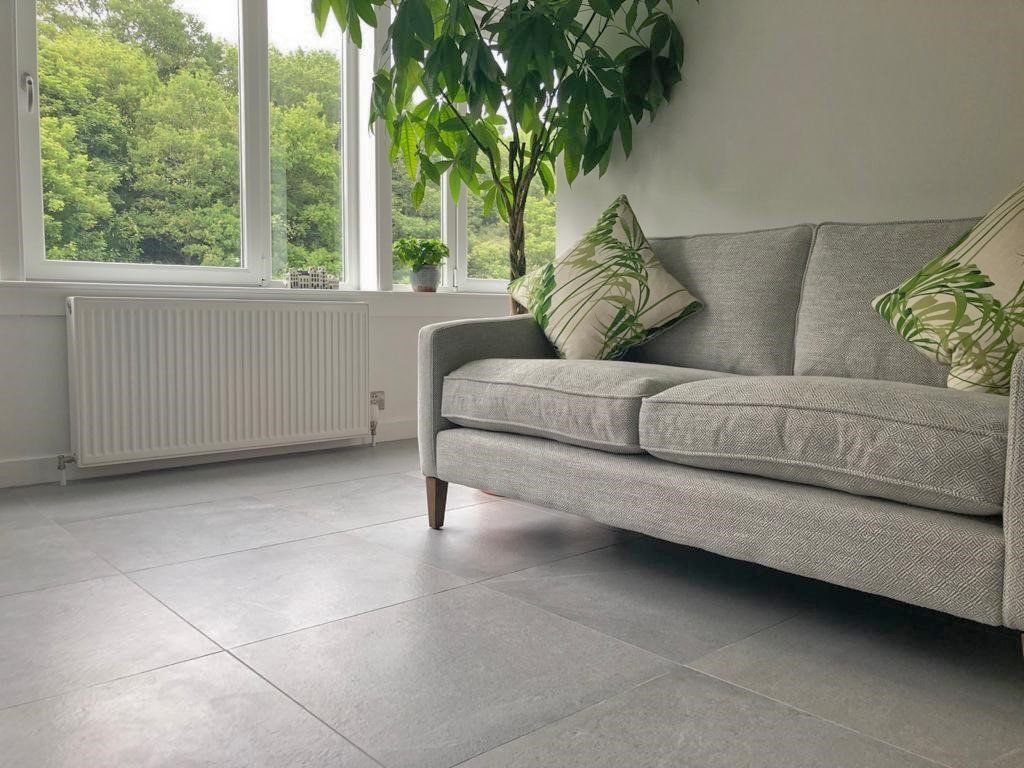 A couch is sitting in a living room next to a window.