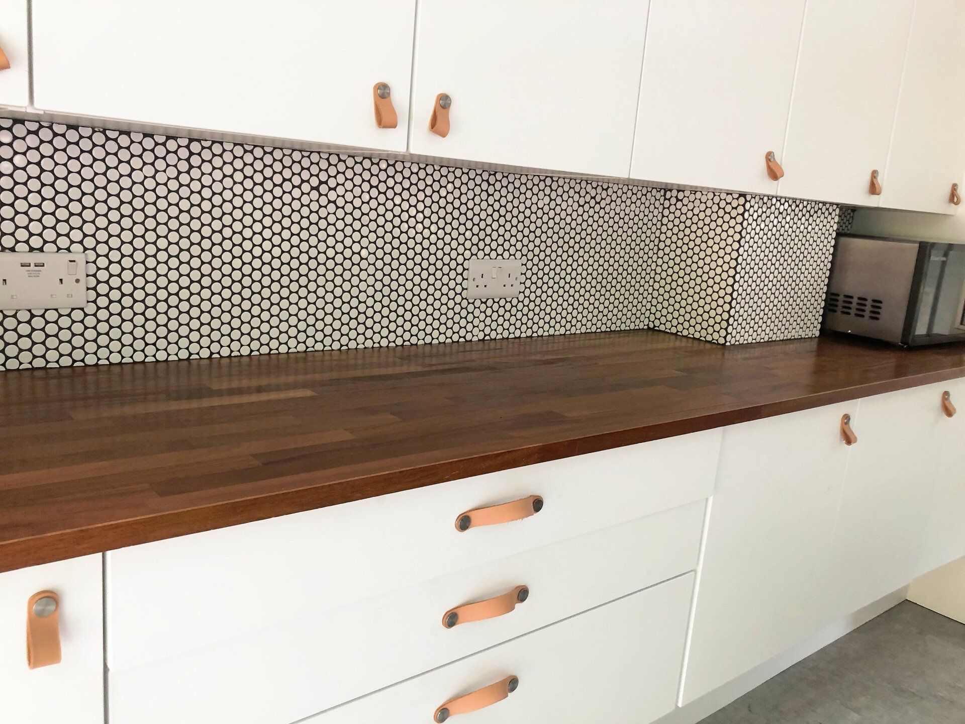 A kitchen with white cabinets and a wooden counter top.