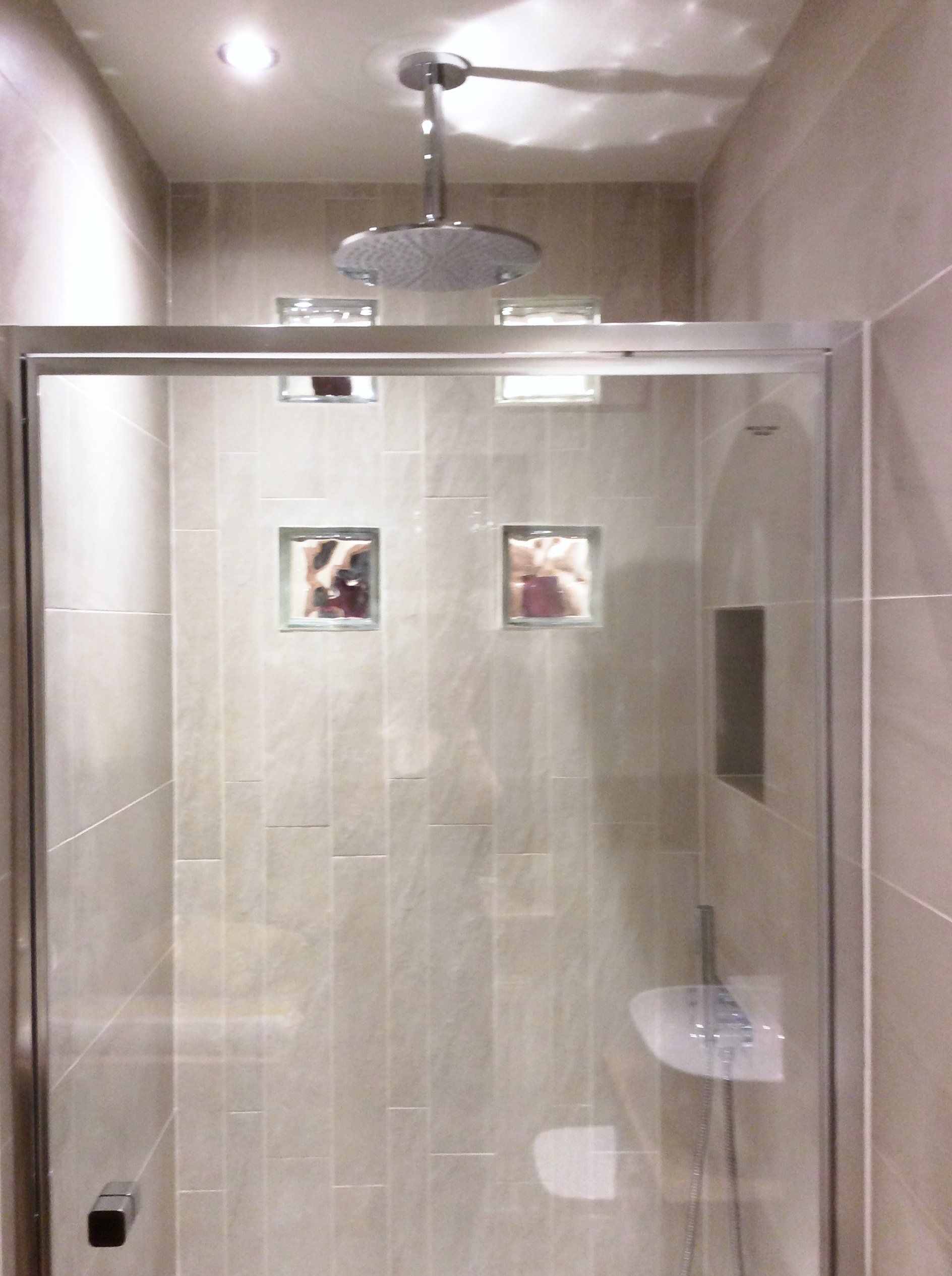 A shower with a sliding glass door and a shower head.
