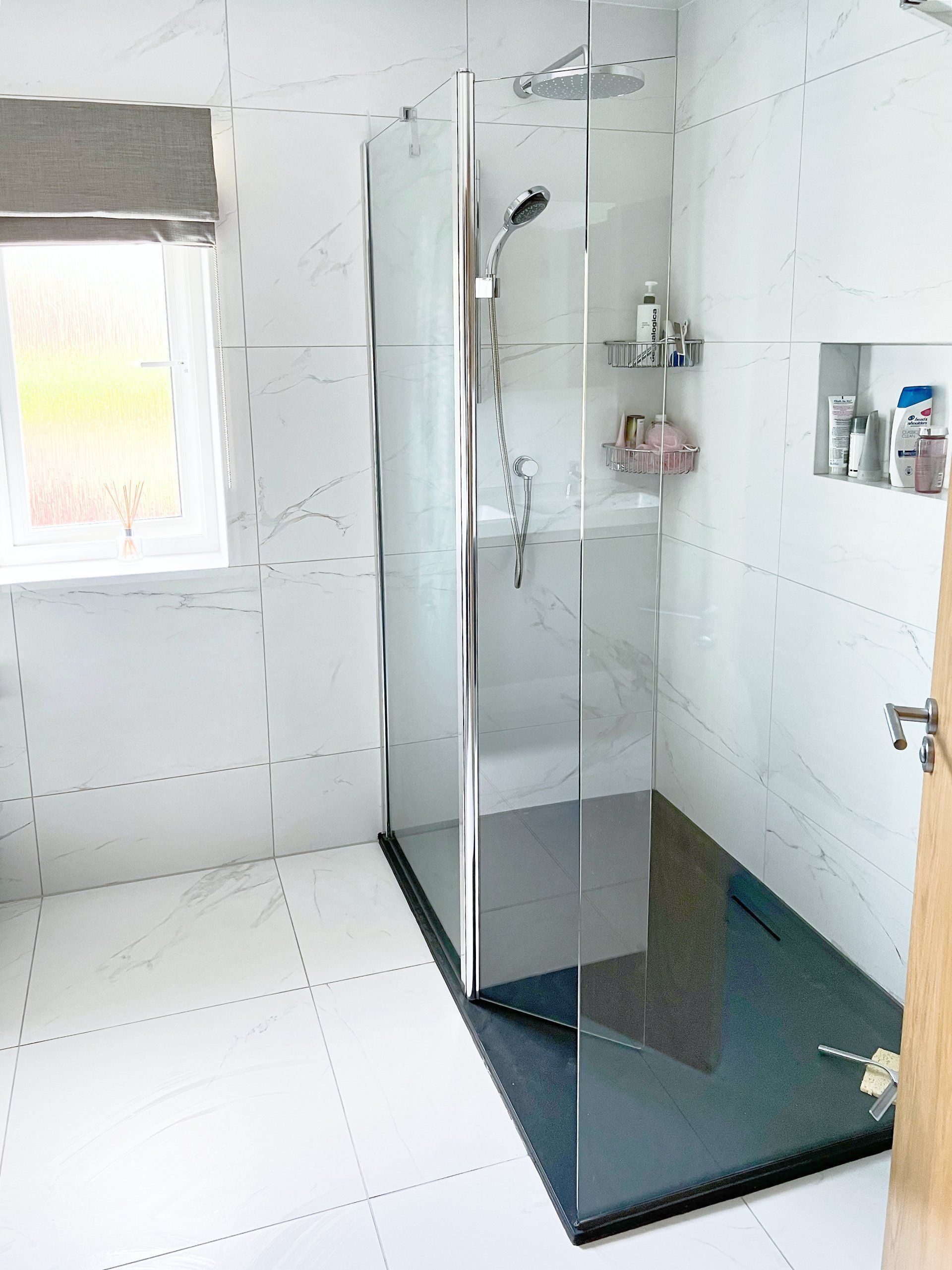 A bathroom with a large walk in shower and a window.