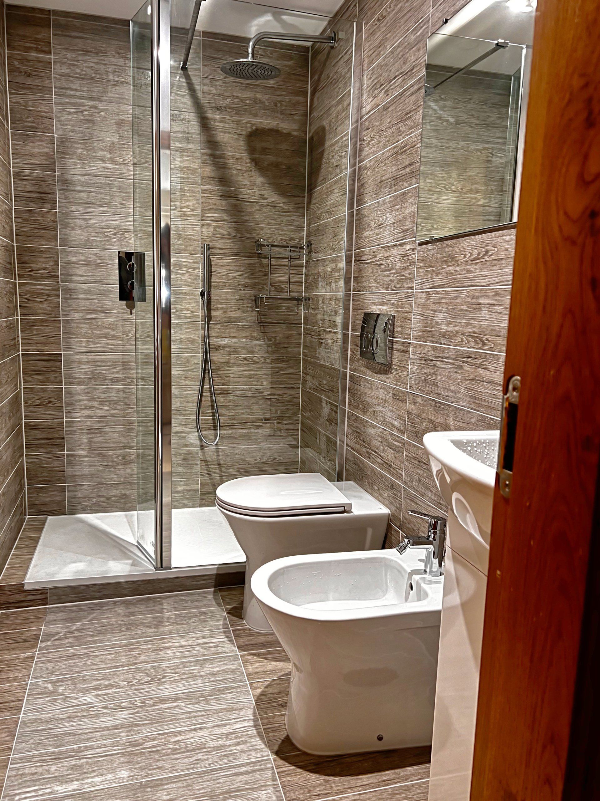 A bathroom with a toilet , bidet , sink and shower.