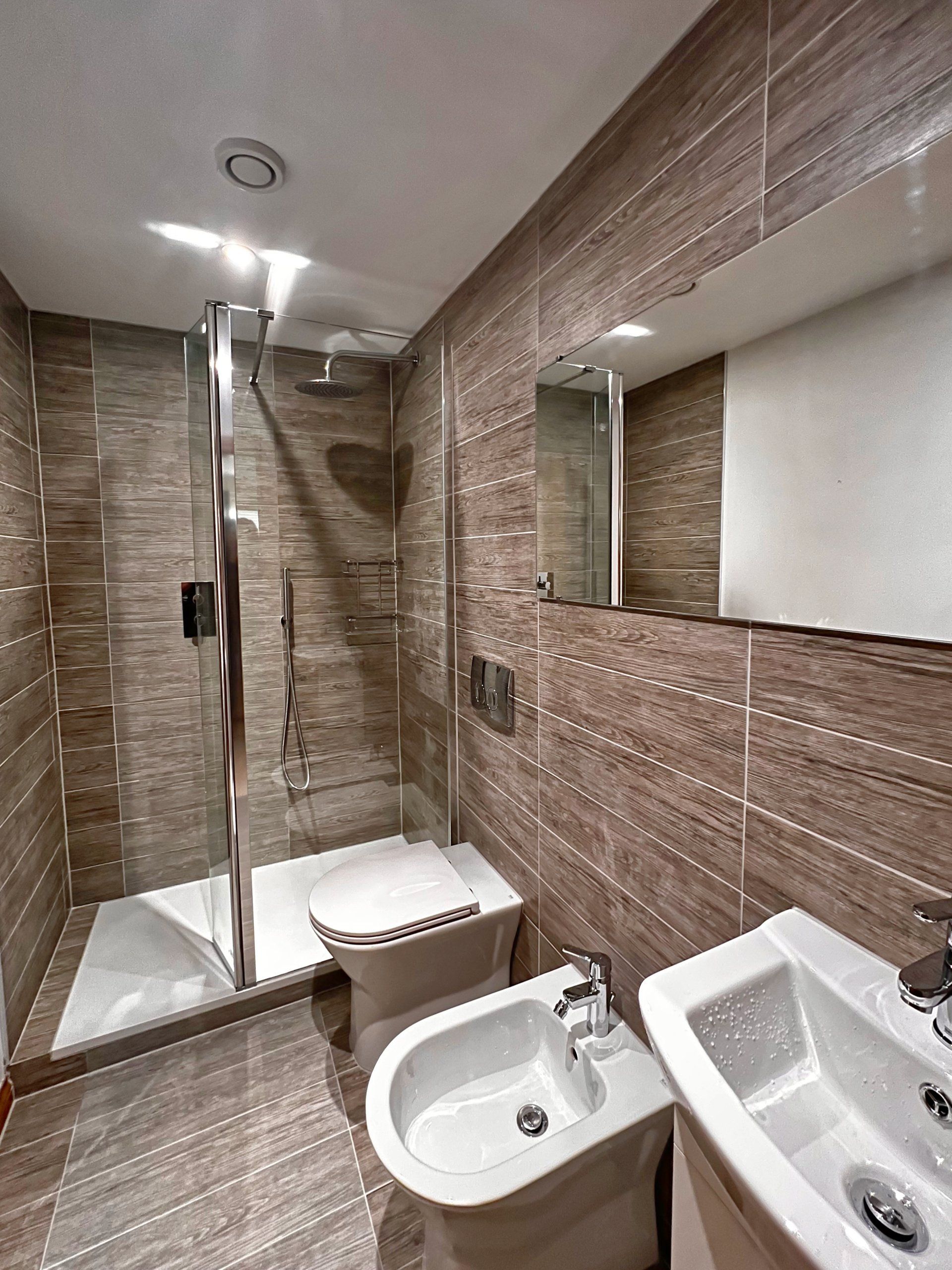 A bathroom with a toilet , bidet , sink and shower.