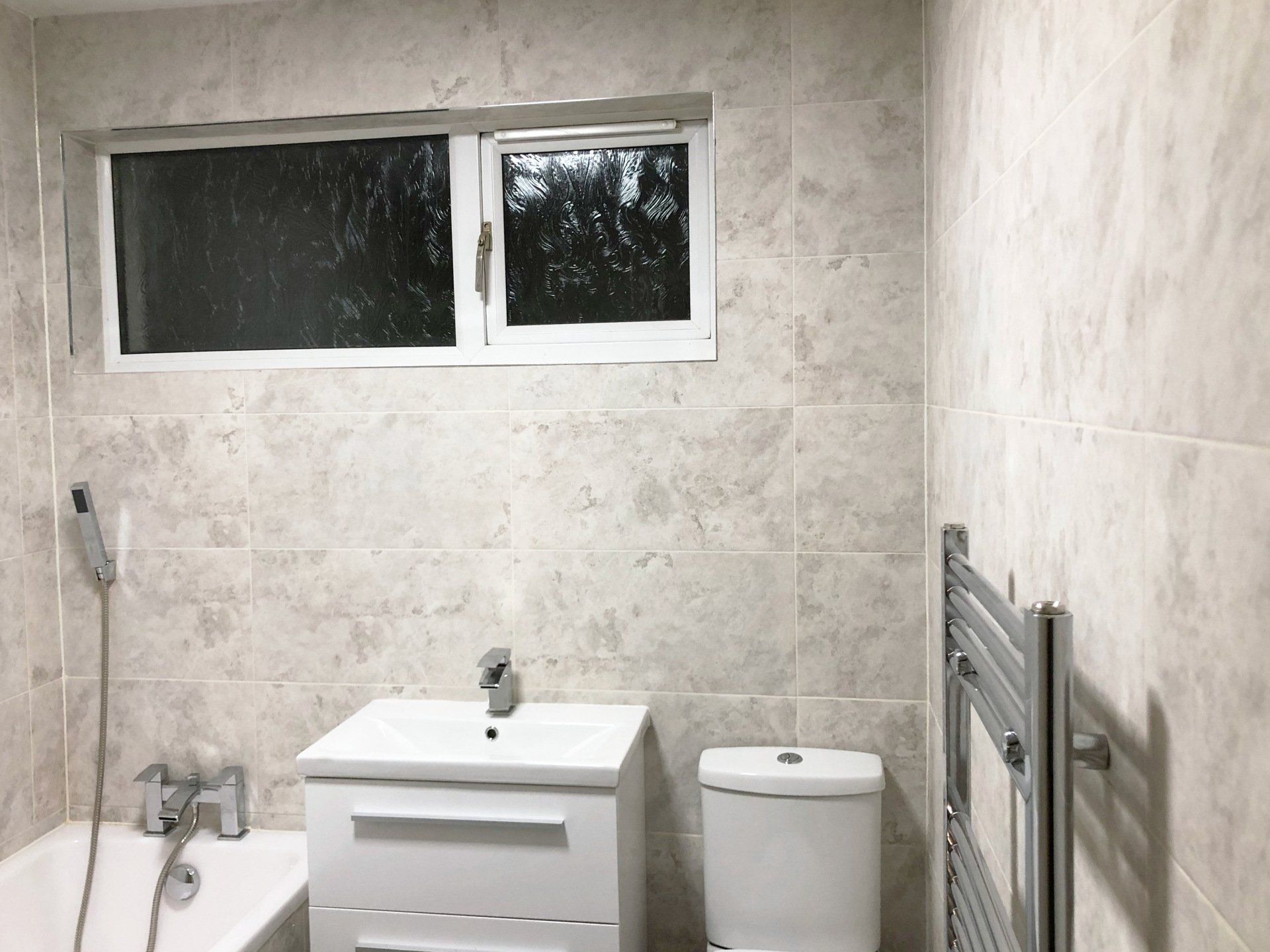 A bathroom with a sink , toilet , bathtub and window.