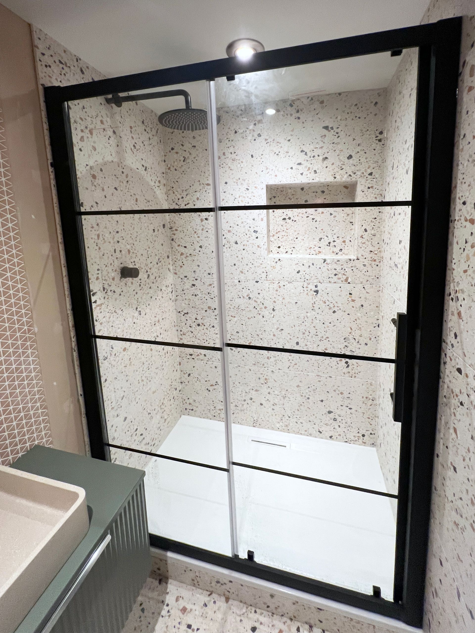 A bathroom with a sliding glass shower door and a sink.