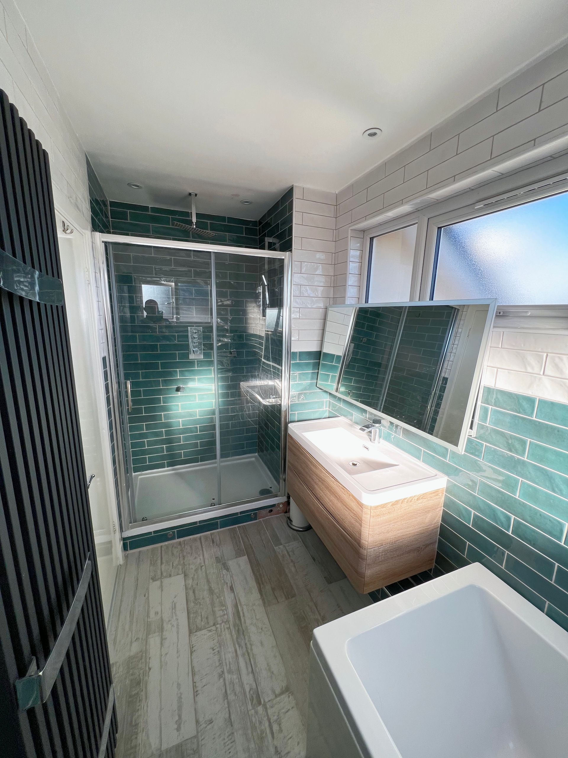 A bathroom with a tub , sink , shower and mirror.