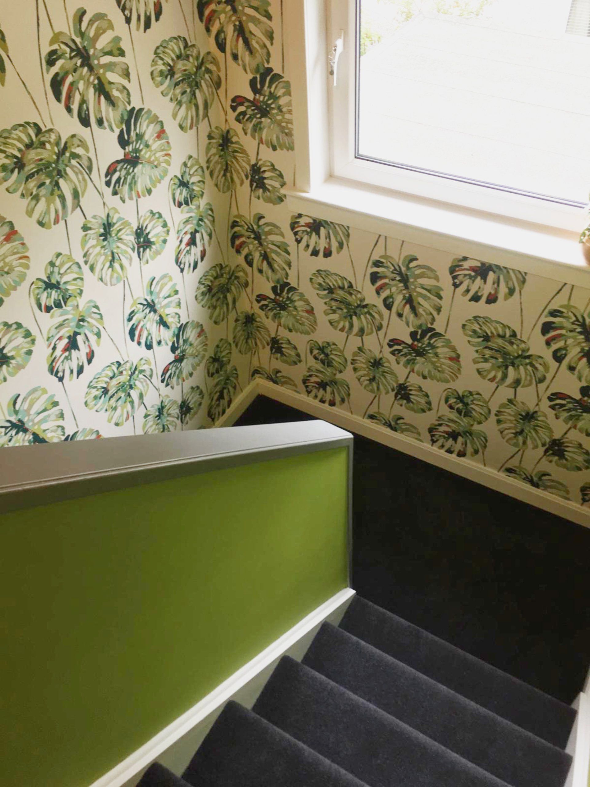 A staircase with a green wallpaper and a window.