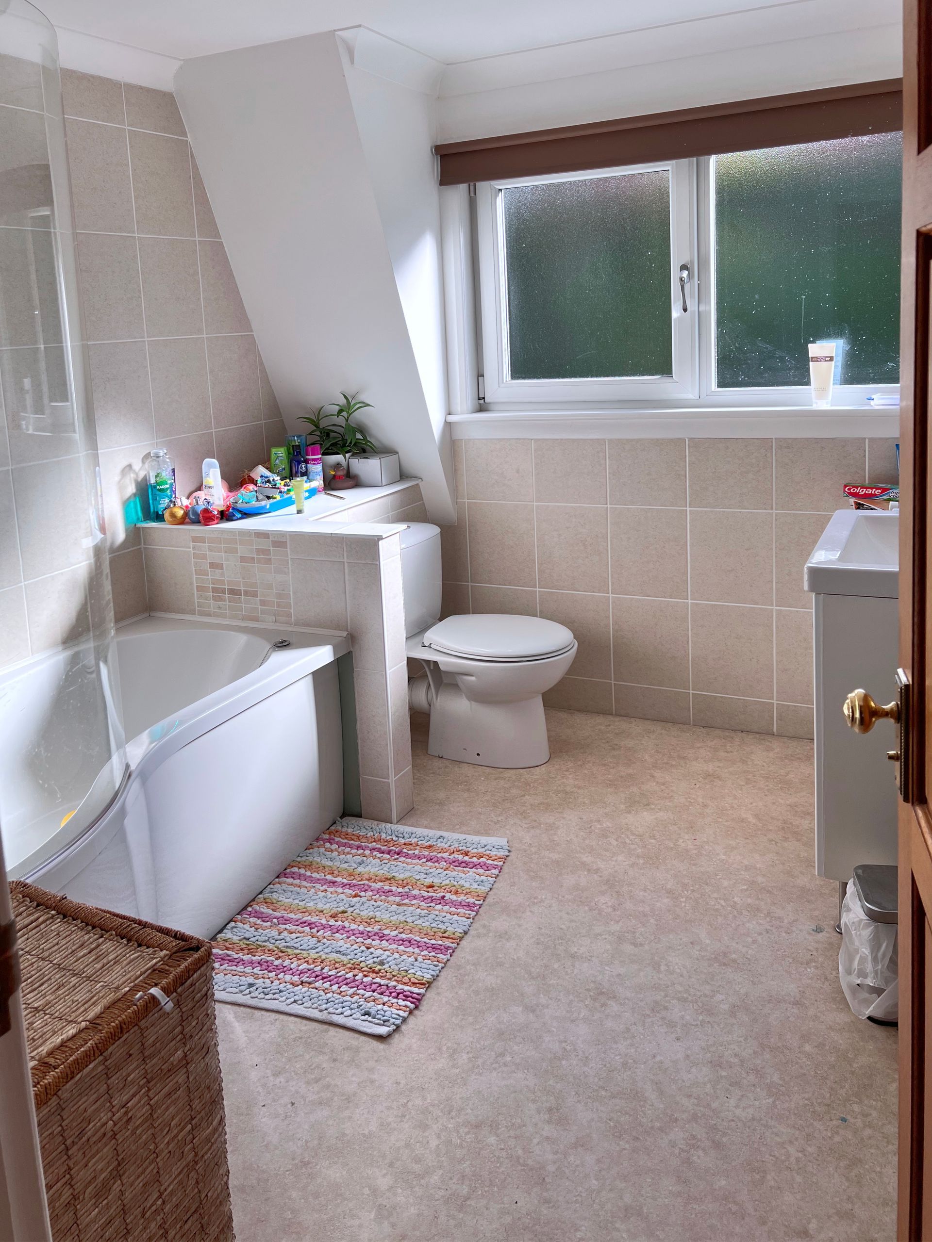 The old bathroom with a tub , toilet , sink and window.