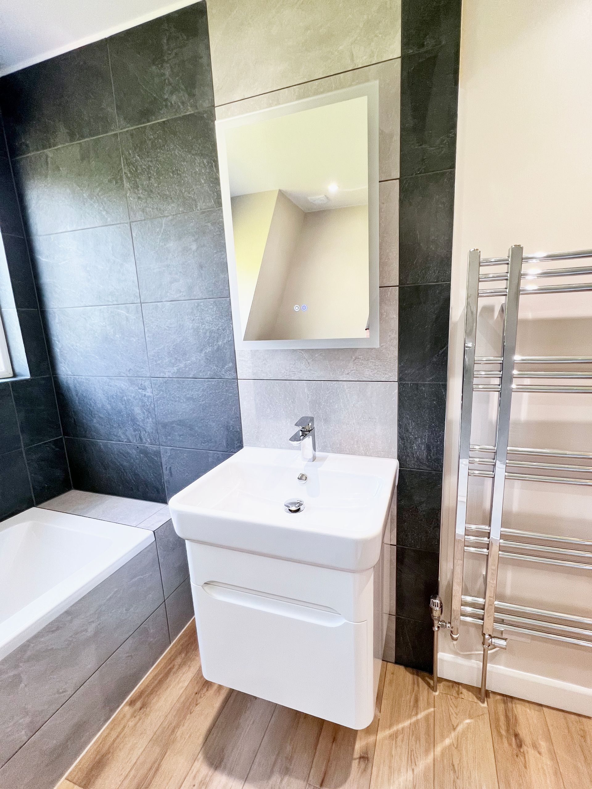 A bathroom with a sink, mirror and towel rack.