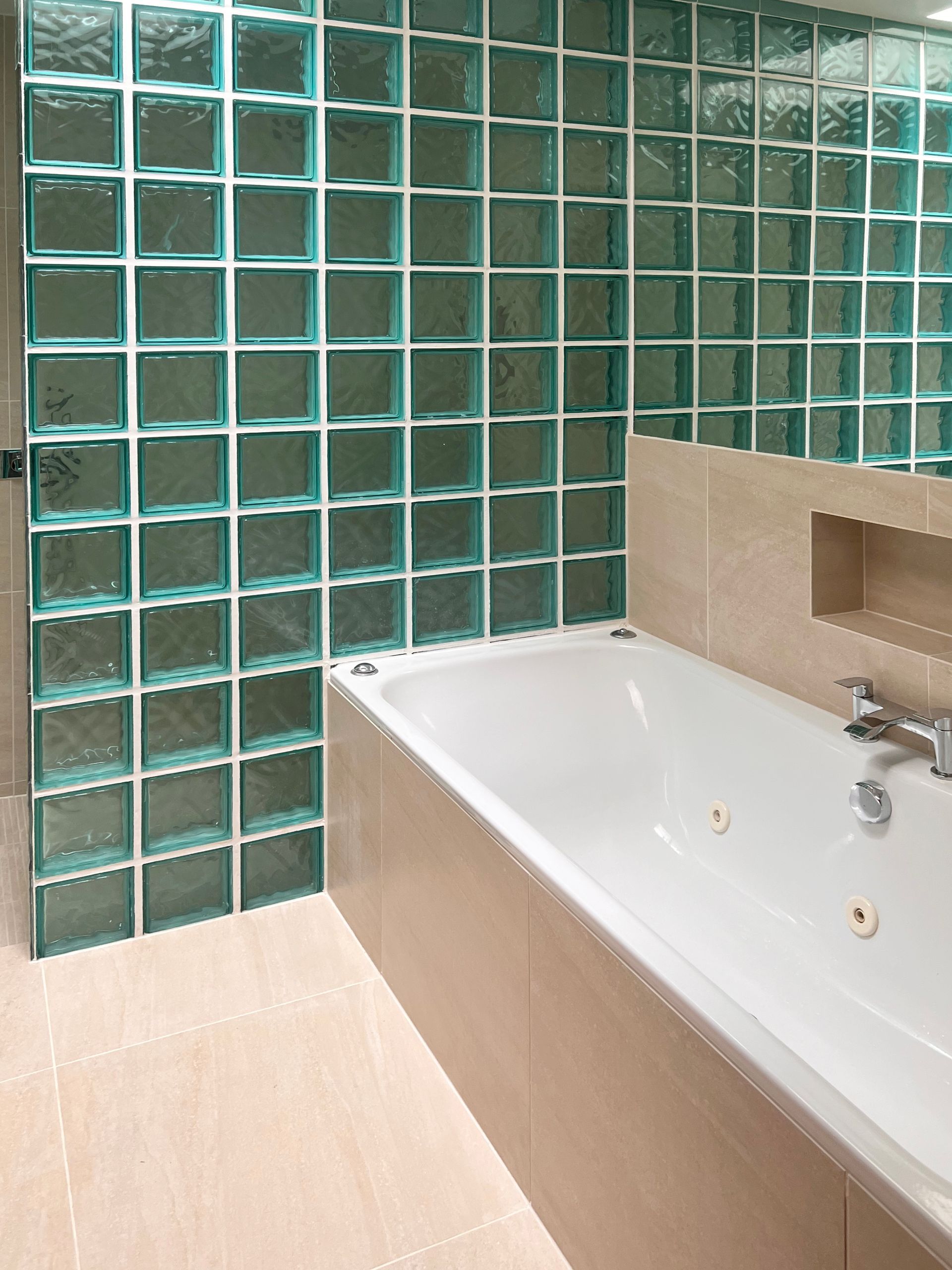 A bathroom with a bathtub and a glass block wall