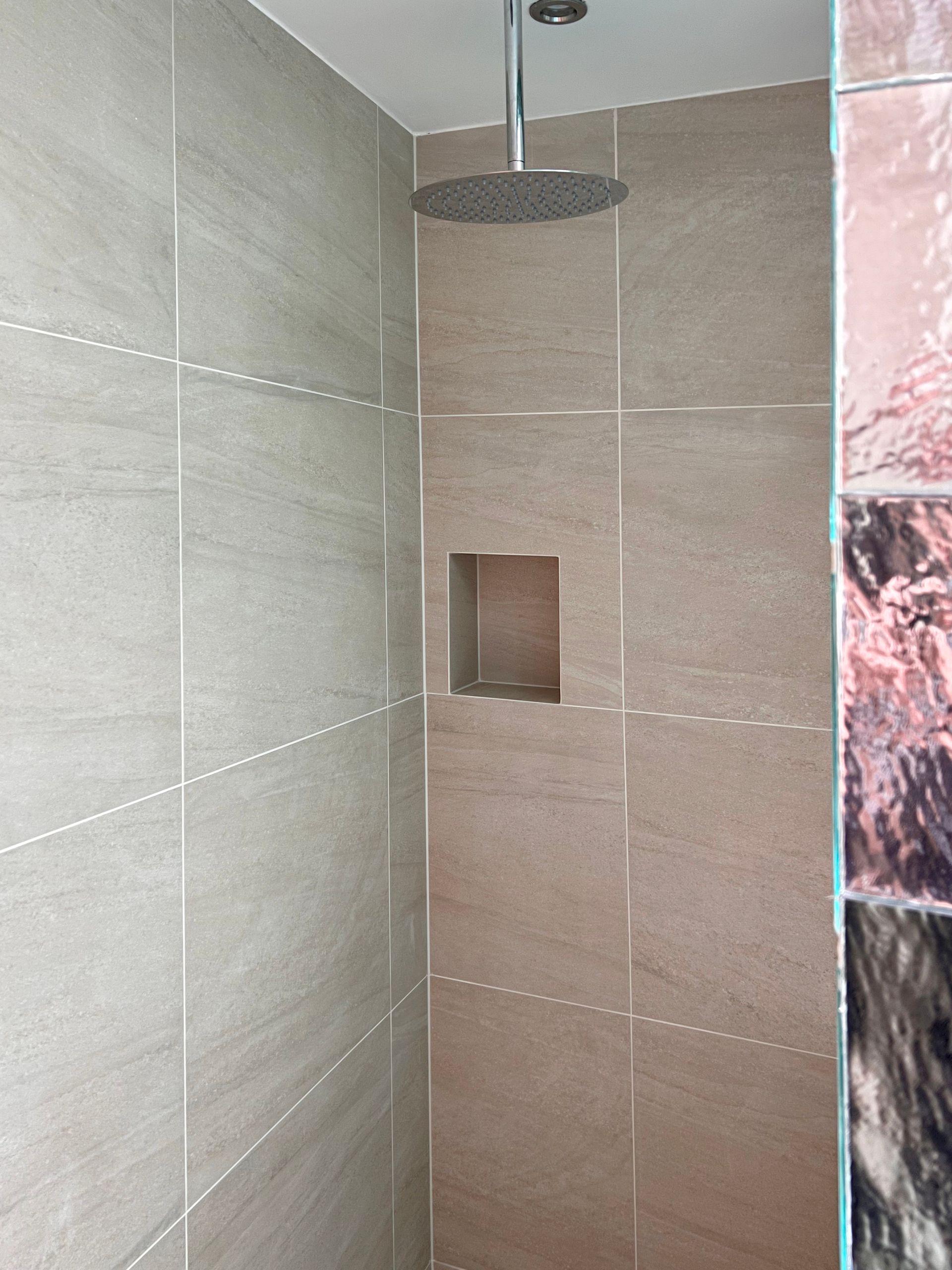 A shower with a shower head hanging from the ceiling.