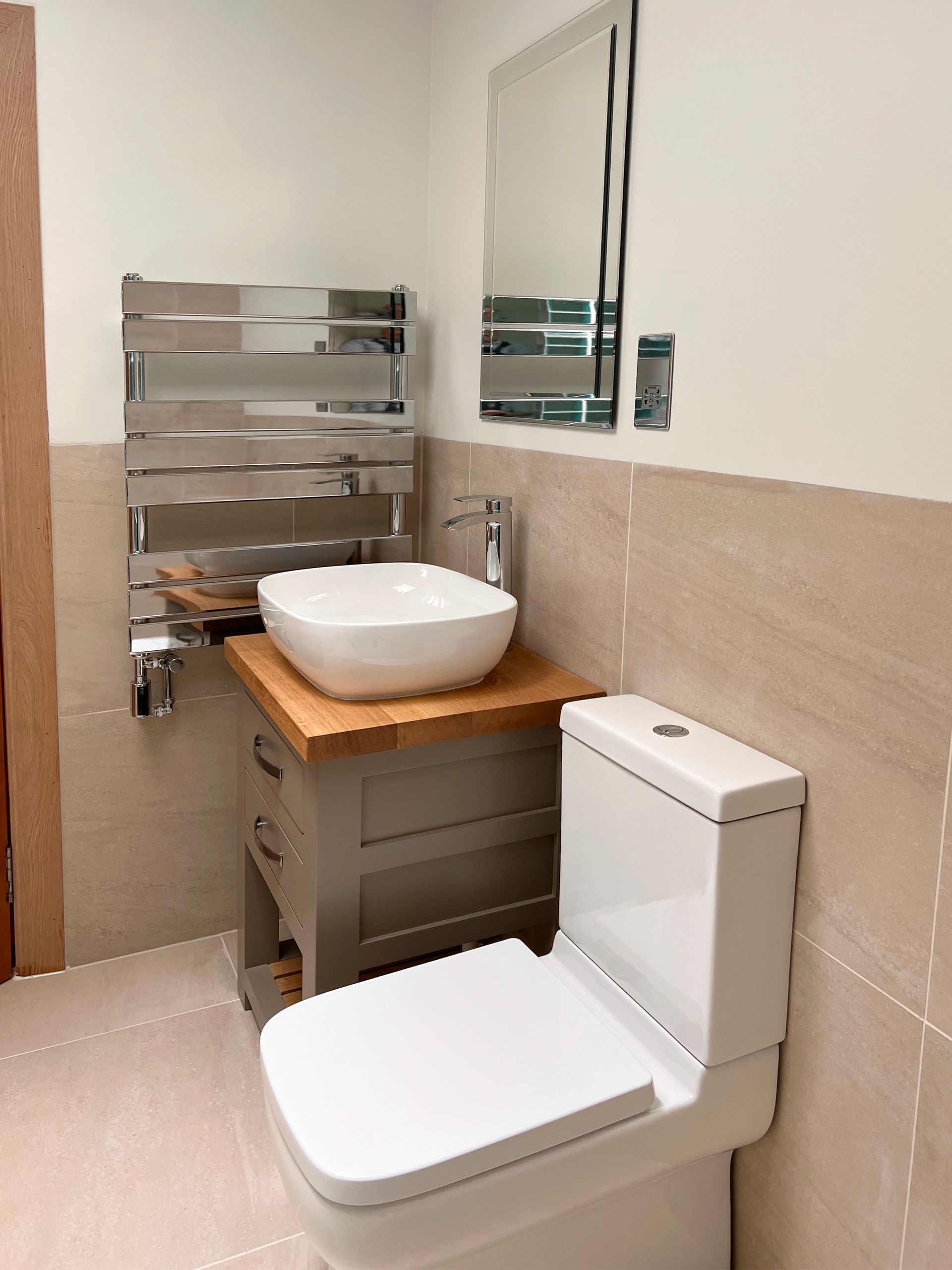 A bathroom with a toilet , modern sink, a towel rack and a mirror.