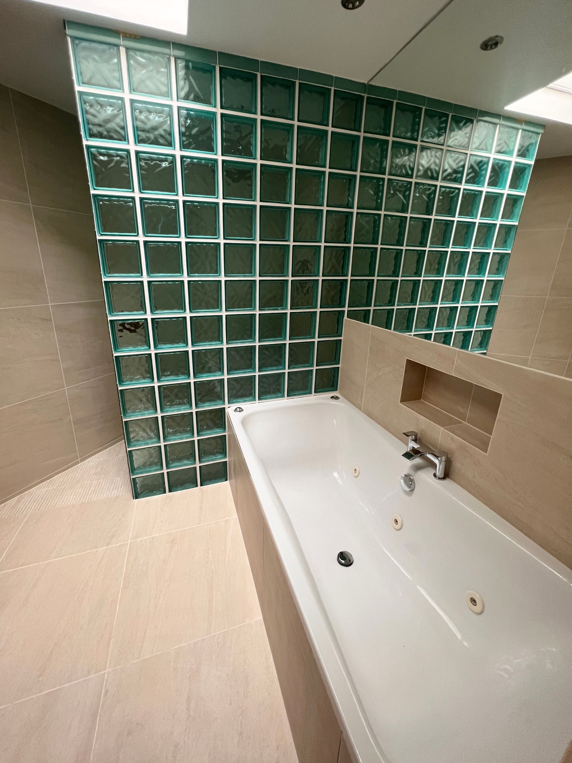A bathroom with a bathtub and a glass block wall.