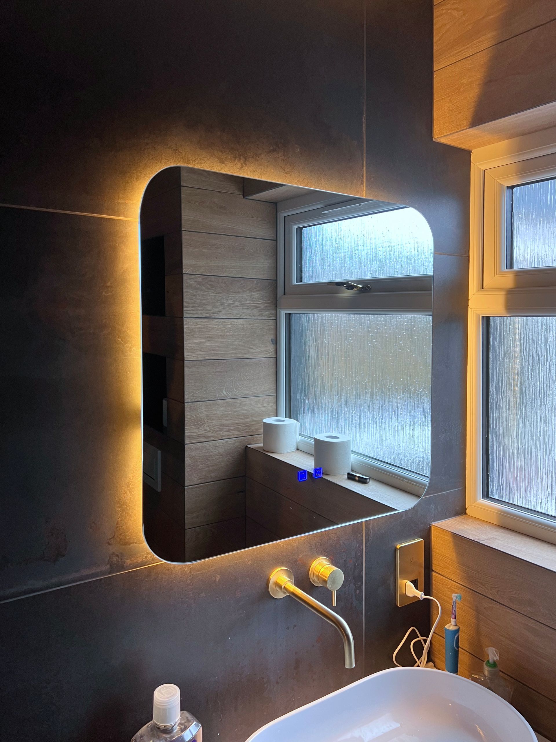 A bathroom with a sink and a mirror with lights on it.