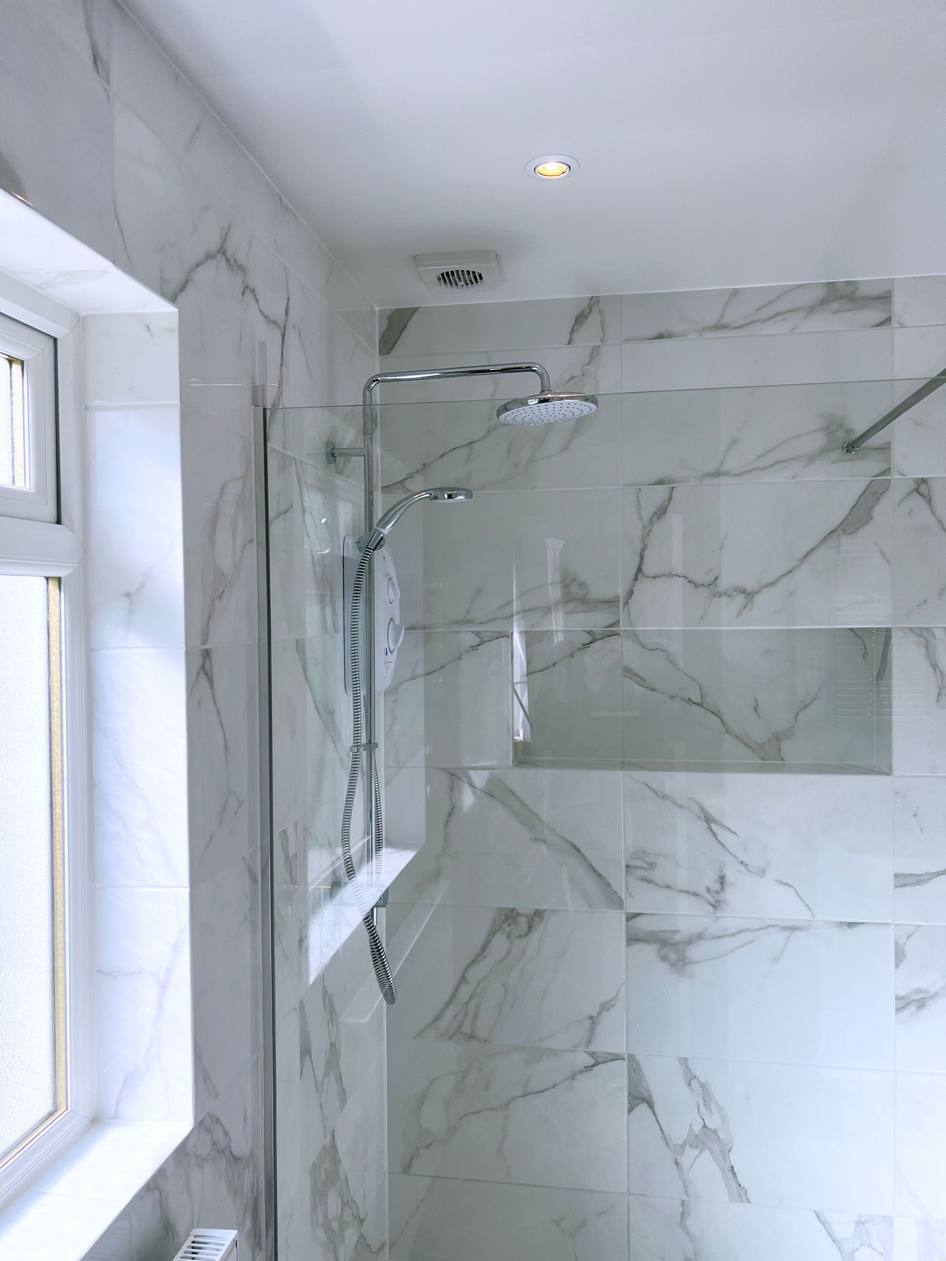 A bathroom with marble tiles and a walk in shower.