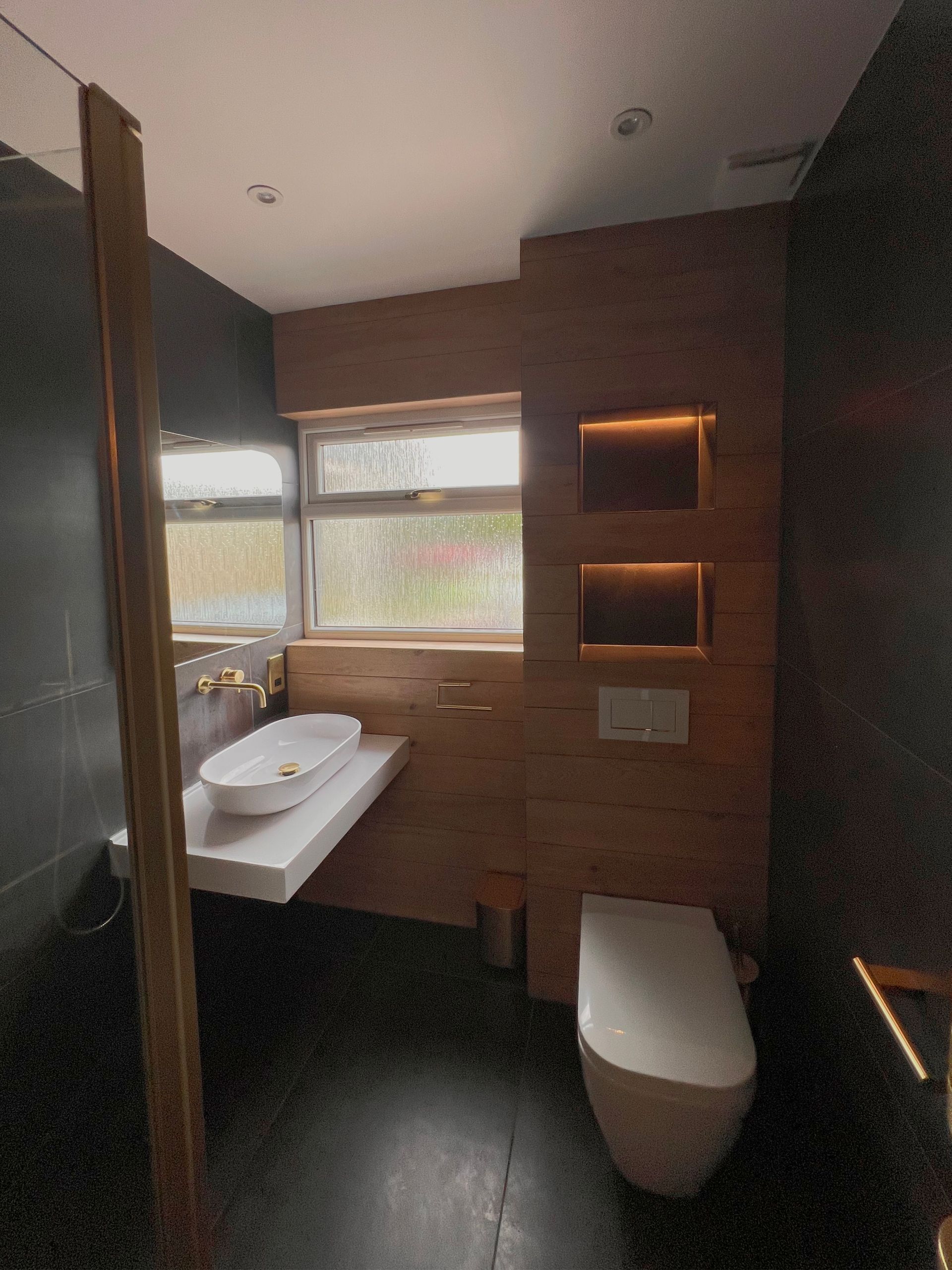 A bathroom with a sink , toilet and window.