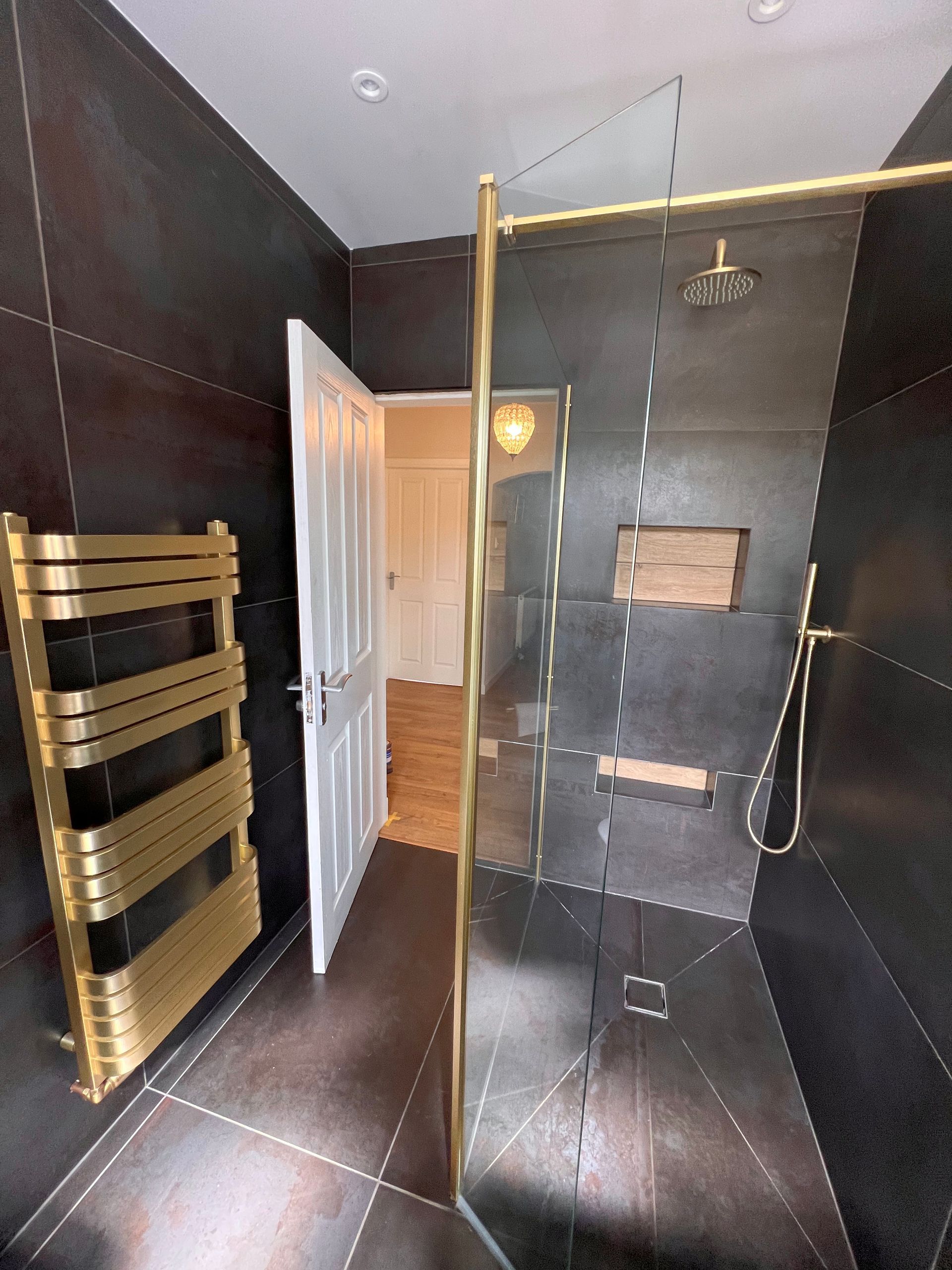 A bathroom with a walk in shower and a gold towel rack.