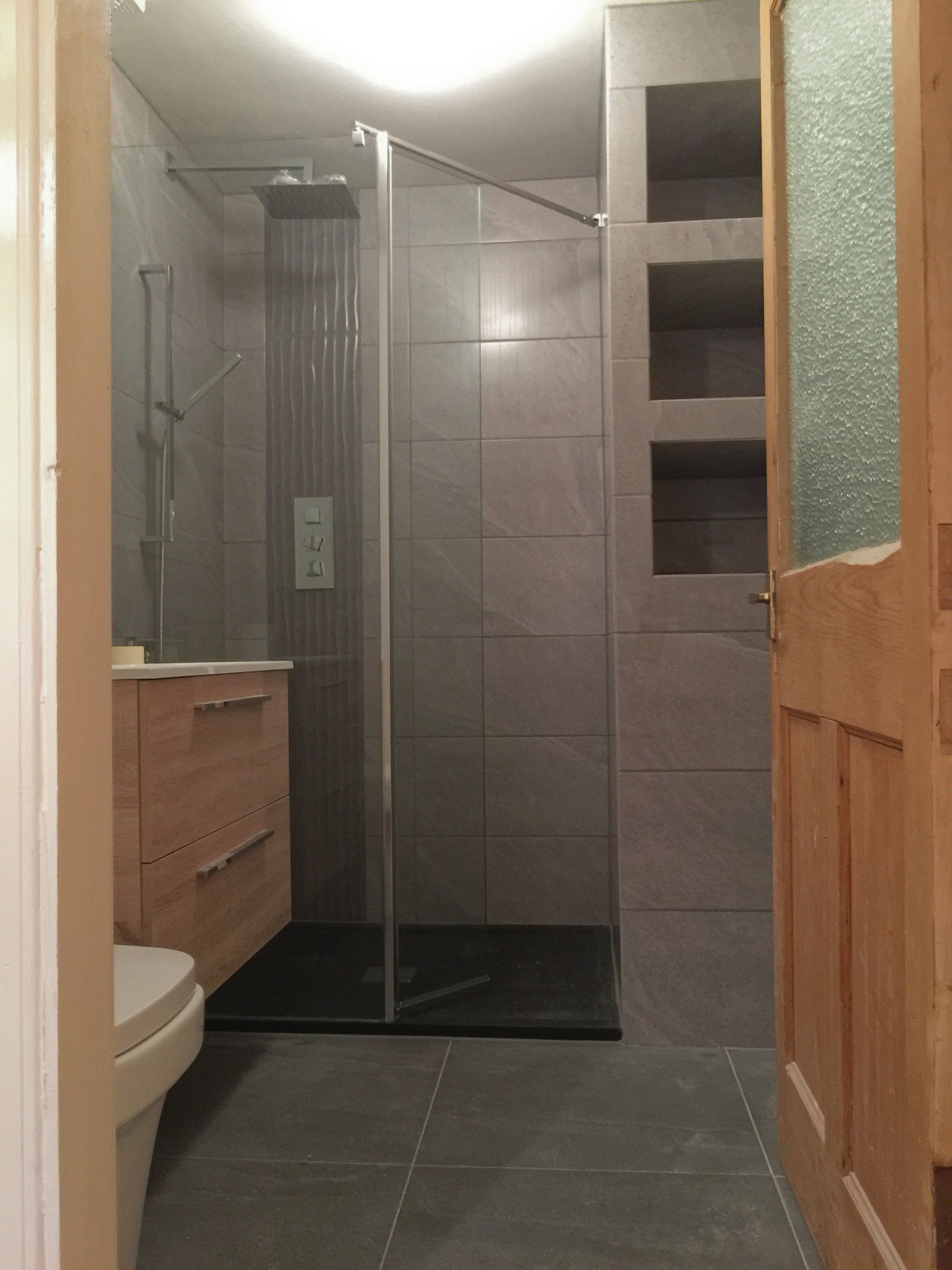 A bathroom with a walk in shower and a toilet.