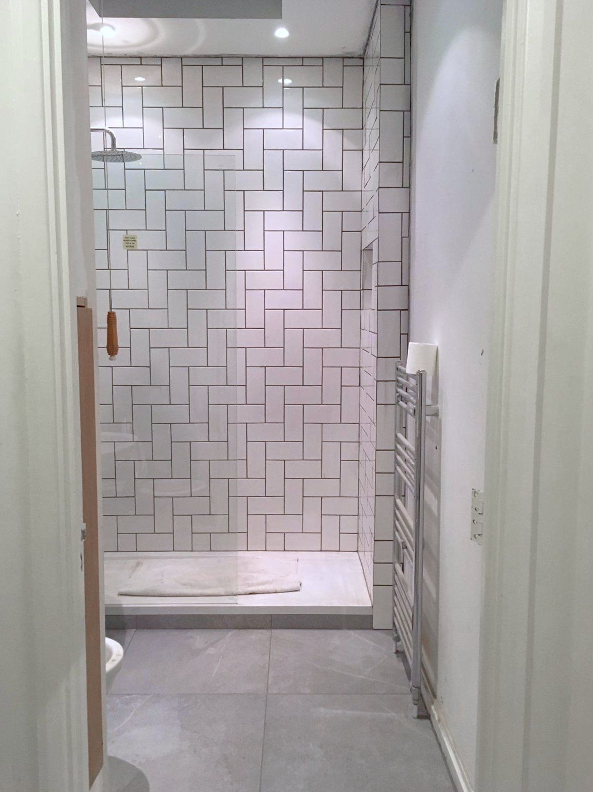 A bathroom with white tiles and a walk in shower.