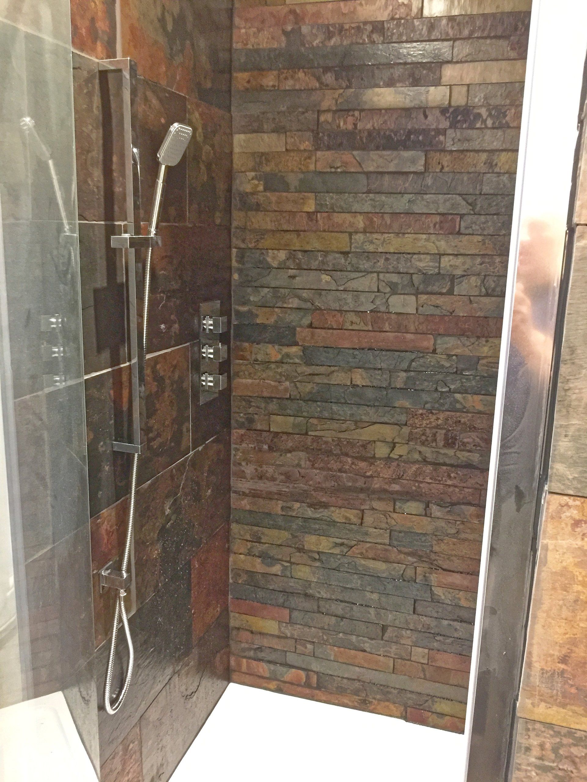 A shower with a brick wall and a shower head.