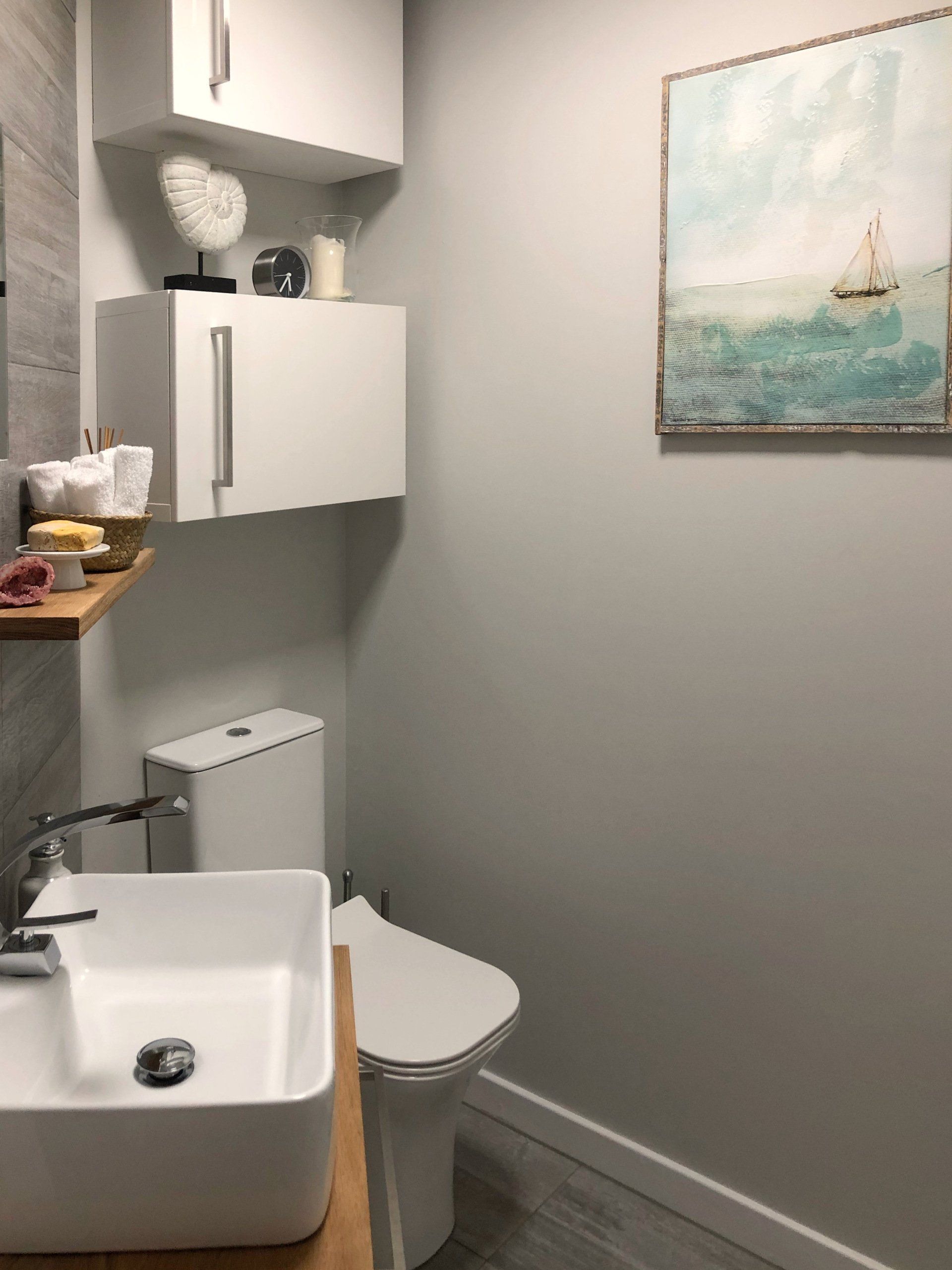 A bathroom with a sink toilet and a painting on the wall