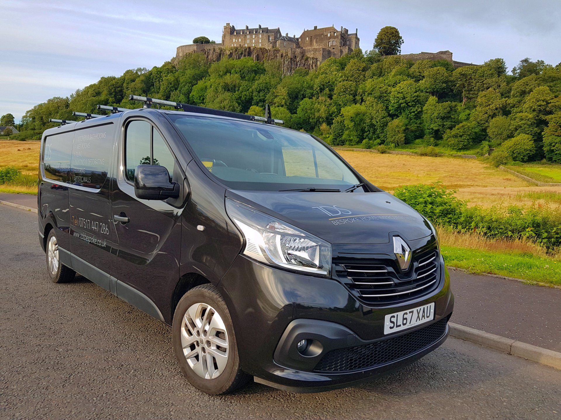 A grey-brown van is parked on the side of the road in front of the Stirling Castle.