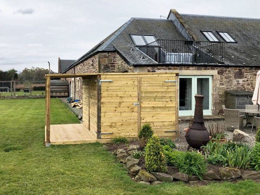 A wooden shed in front of an old stone building. 