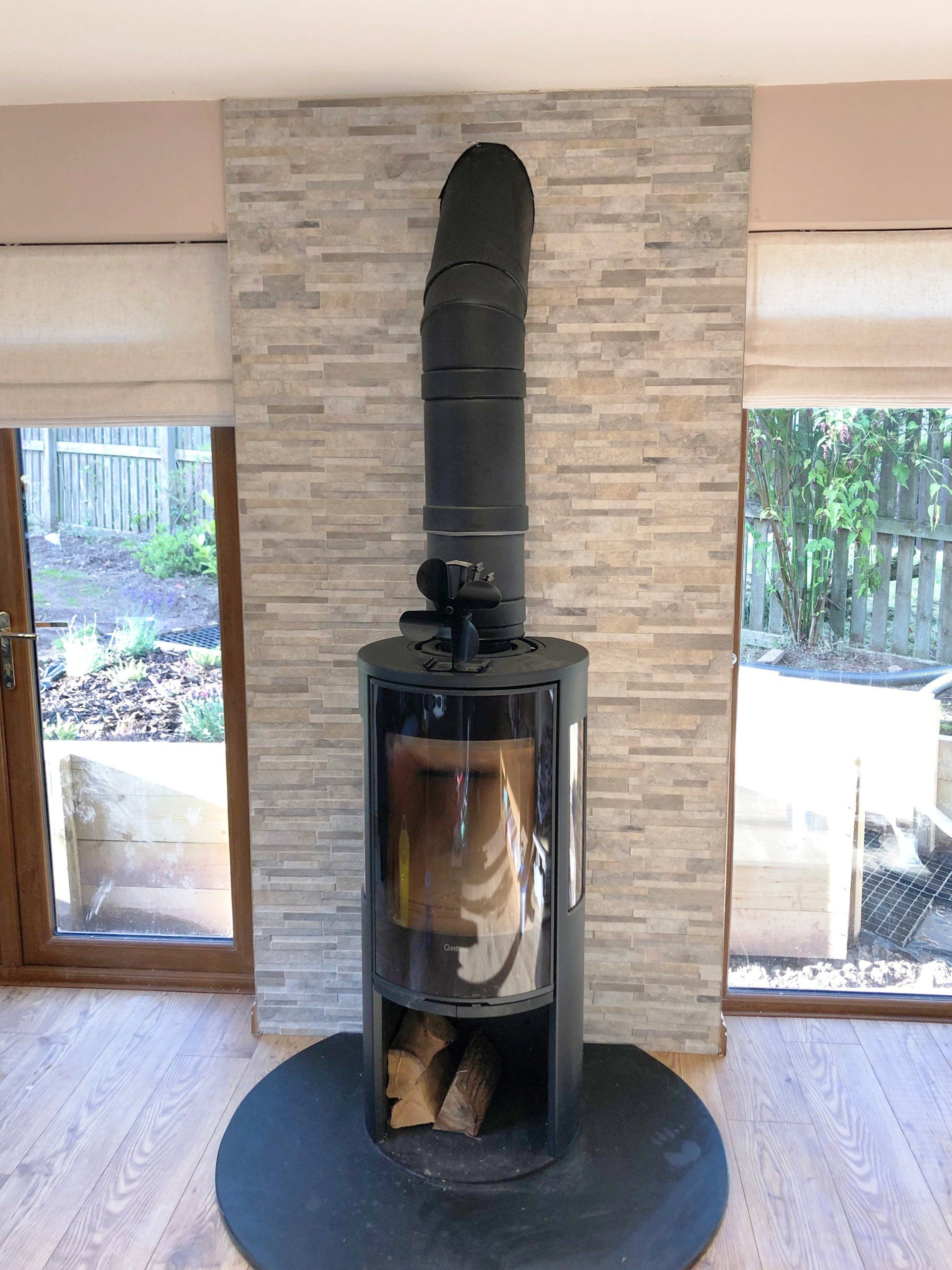A wood stove is sitting in a living room next to a window.