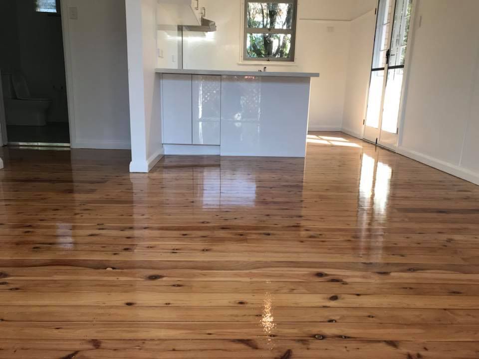 A Kitchen With A Wooden Floor And White Cabinets — Byron Floor Sanding In Lismore, NSW
