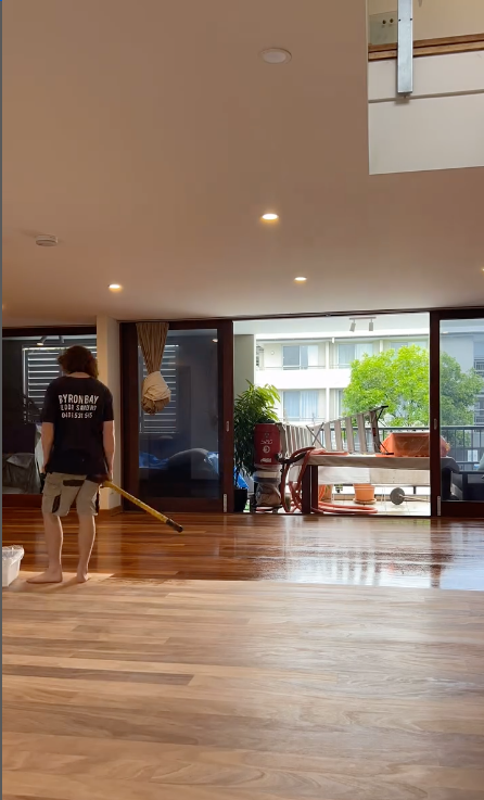 A Man Standing With A Mop Polishing A Wooden Floor — Byron Floor Sanding In Byron Bay, NSW