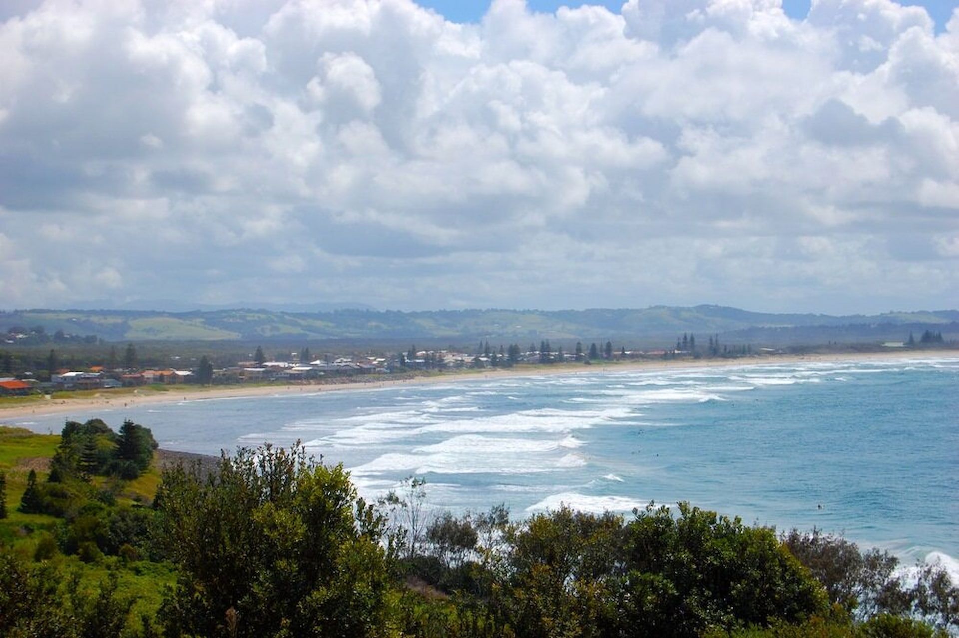 Ocean coastline with a town along the shore under a cloudy sky — Byron Floor Sanding In Lennox Head, NSW