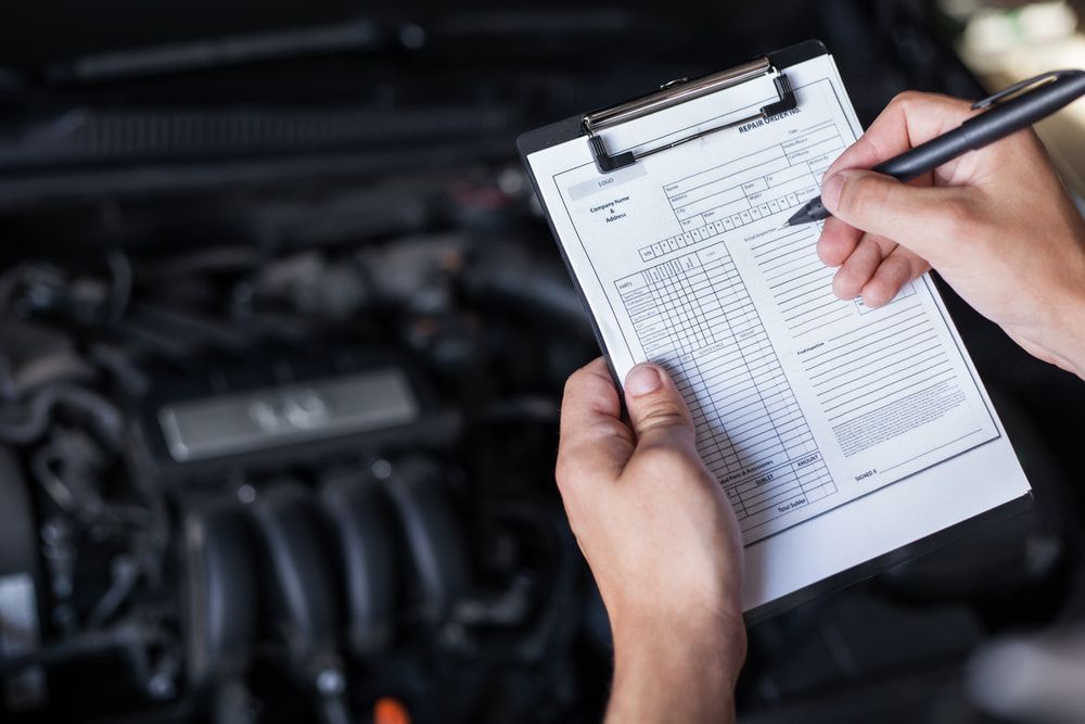 A Person is Writing on a Clipboard in Front of a Car Engine — Steve's Service Centre in Albury, NSW