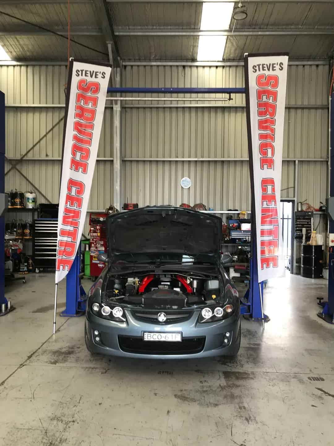 A Car is Sitting on a Lift in a Garage With the Hood Up — Steve's Service Centre in Albury, NSW 
