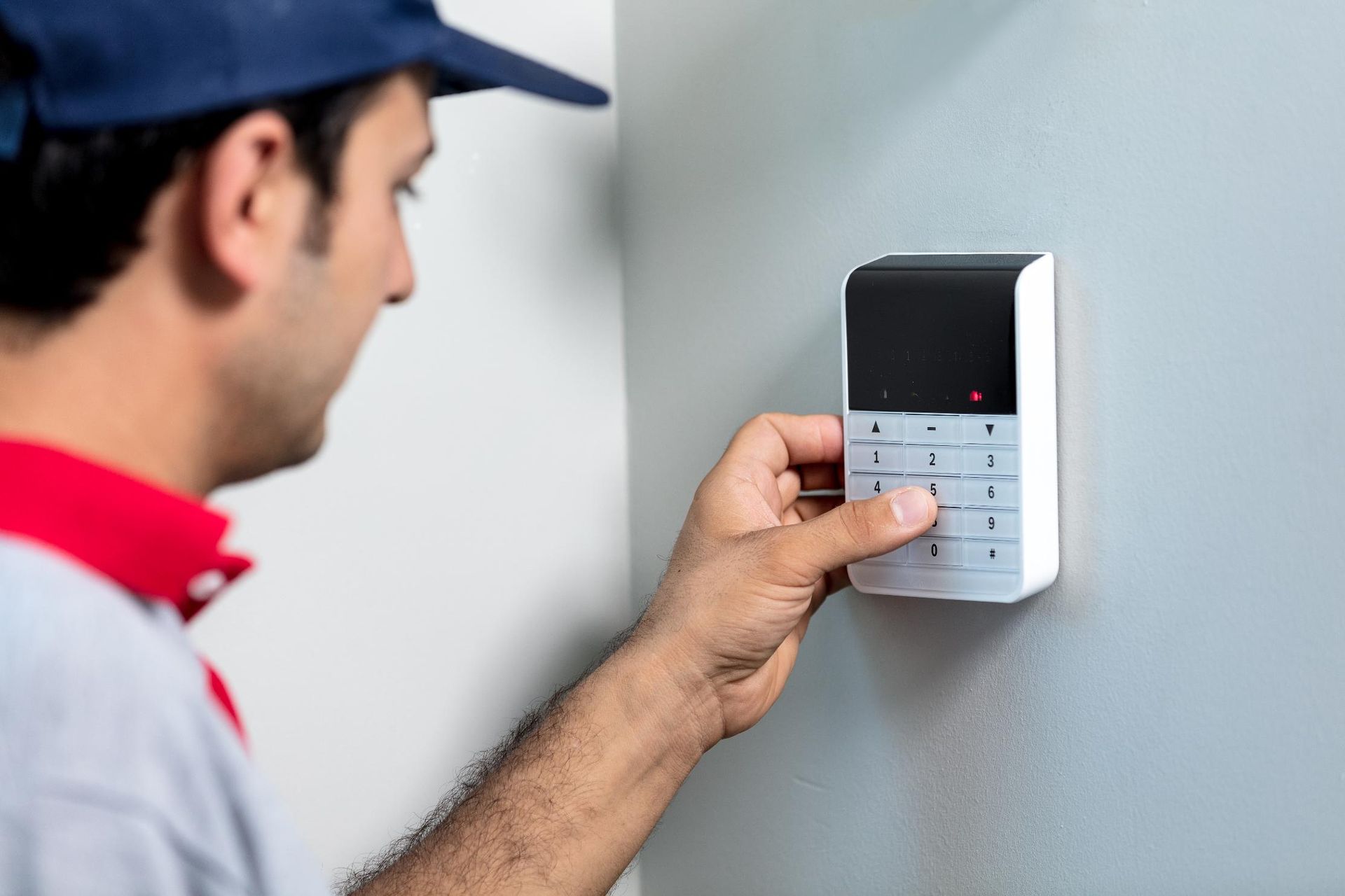 Man in uniform enters code on a wall-mounted security keypad.