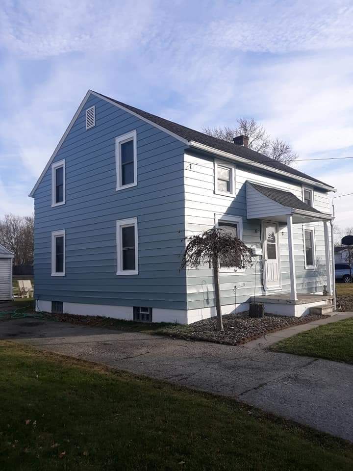A two-story house with blue horizontal siding, white trim, a gabled roof, and a small covered entryway.