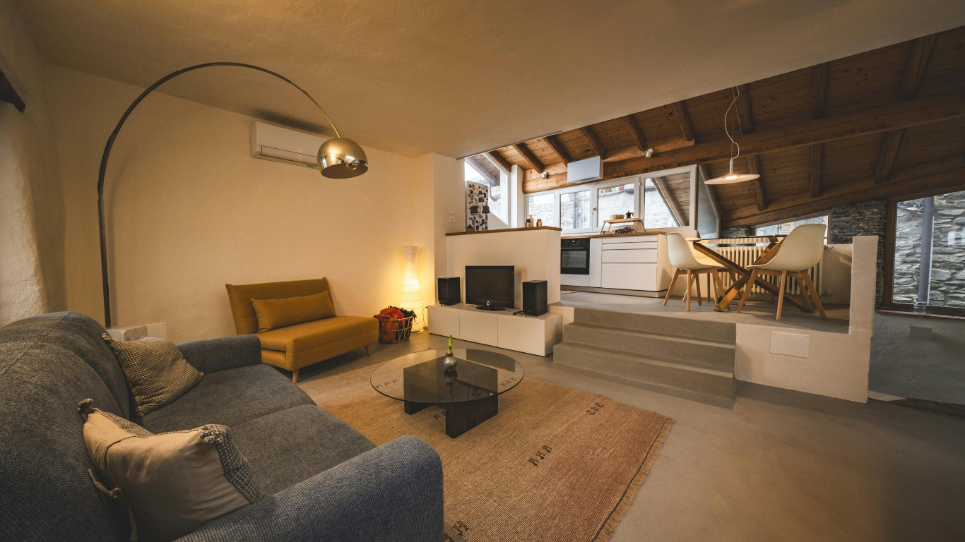 Cozy living space with sofa, yellow loveseat, and raised kitchen area.