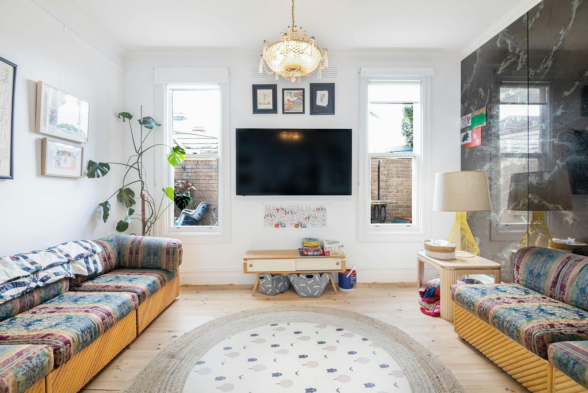 Living room with white walls, two patterned sofas, a large TV, and a decorative rug.