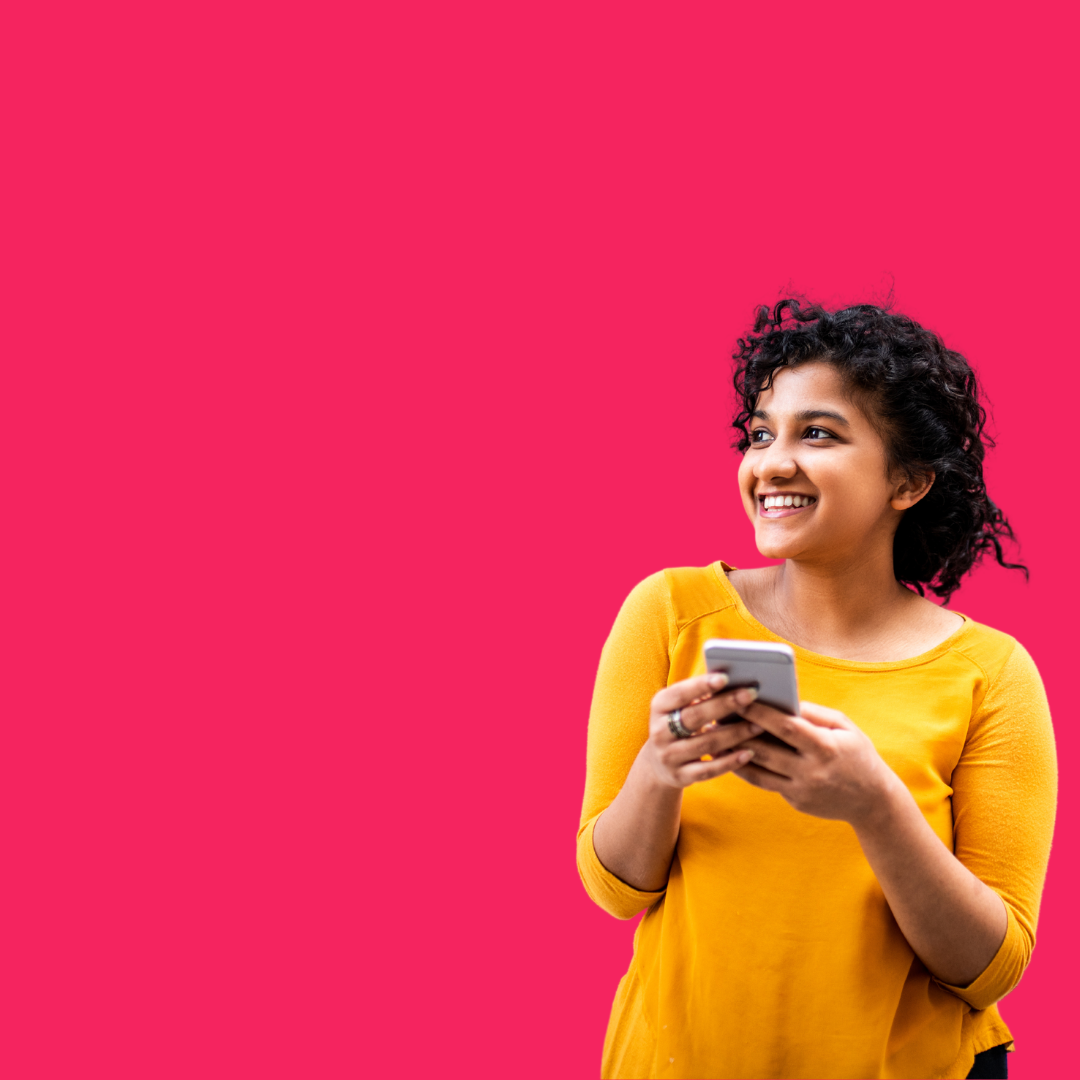 A woman in a yellow shirt is holding a cell phone and smiling.